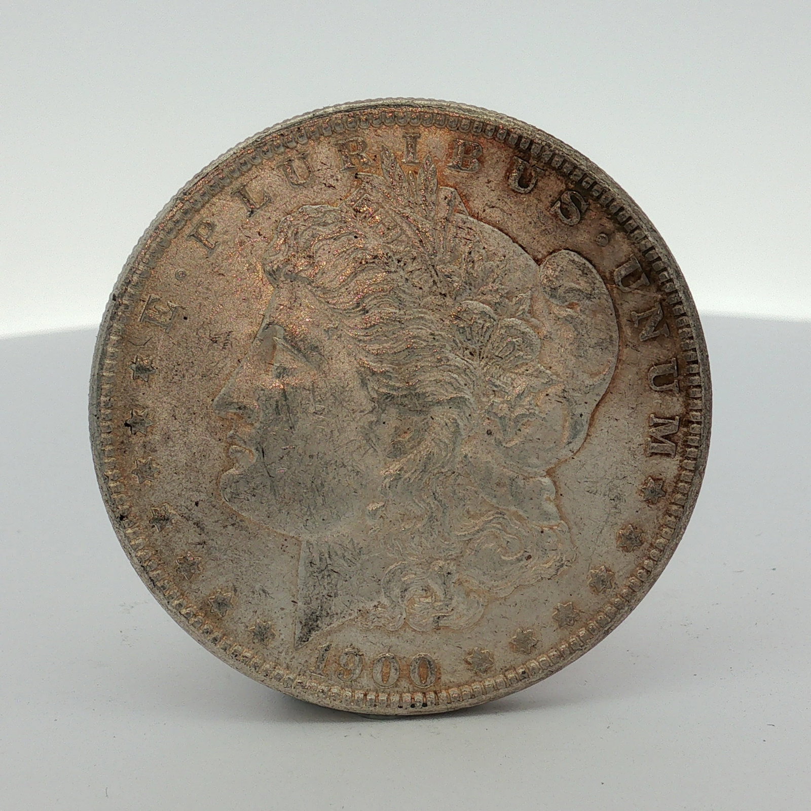 1900-O US Morgan Silver Dollar: This US Morgan dollar is dated 1900 and bears the O mint mark for the New Orleans Mint on the reverse above the DO in DOLLAR. The coin is struck in 90% silver and 10% copper with a reeded edge. It fea