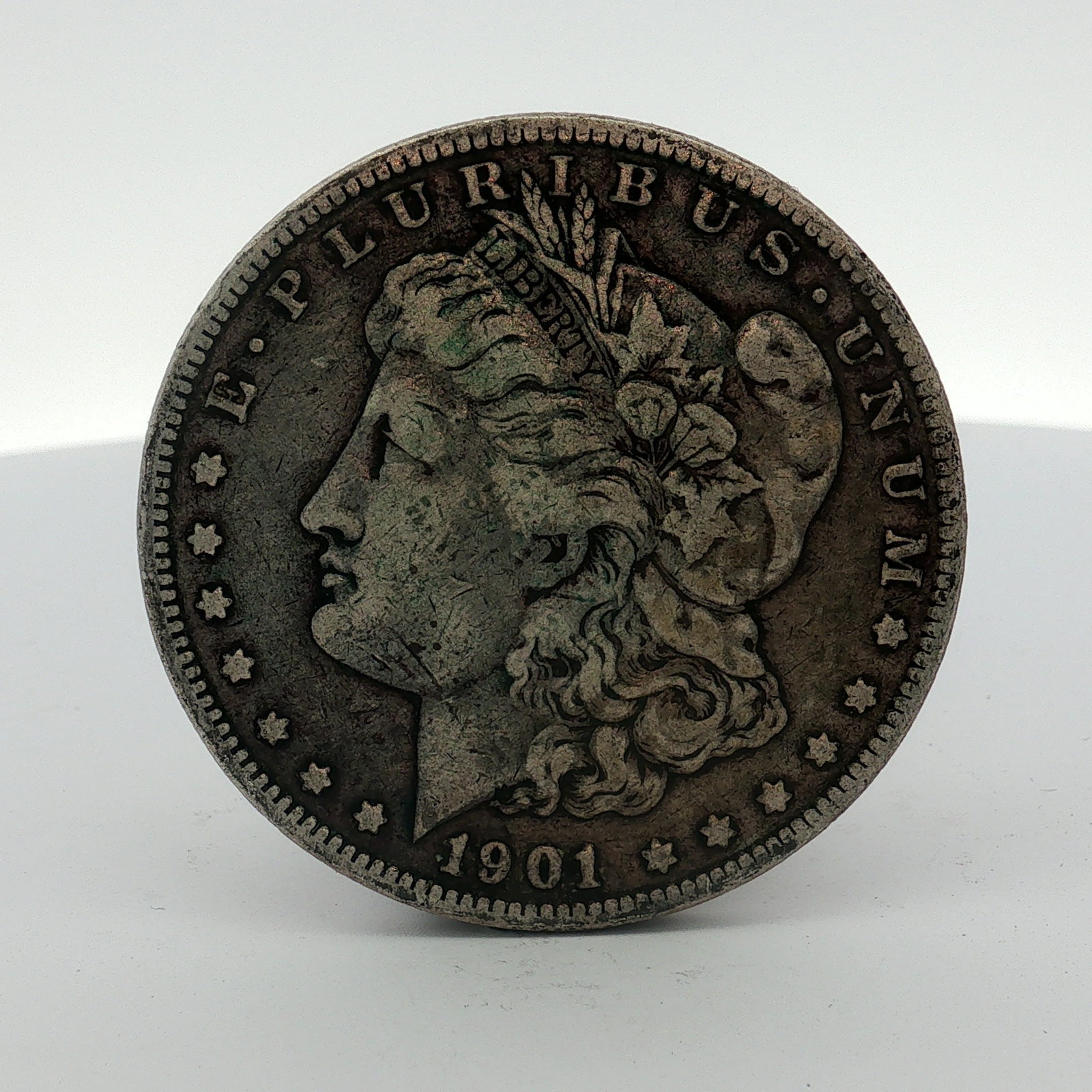 1901-O US Morgan Silver Dollar: 1901-O US Morgan Silver Dollar struck at the New Orleans Mint. This coin is composed of 90% silver and 10% copper. The obverse features the Liberty Head design with the legend E PLURIBUS UNUM, thirtee