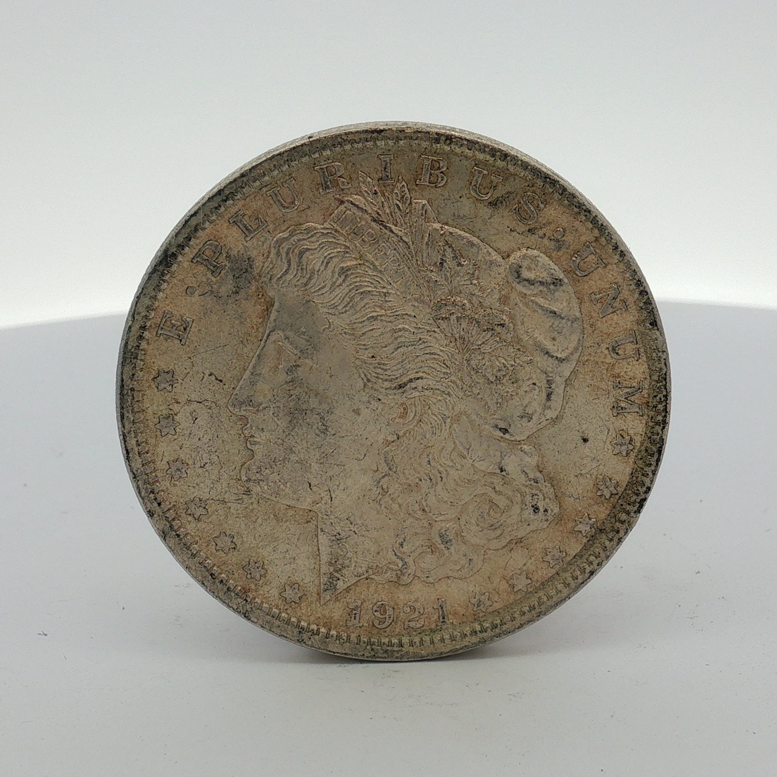 1921 US Morgan Silver Dollar Coin Circulated: This 1921 US Morgan Silver Dollar is struck in 90% silver and 10% copper. The obverse features the Liberty head design type with the date 1921 and the legend E PLURIBUS UNUM. The reverse features the 