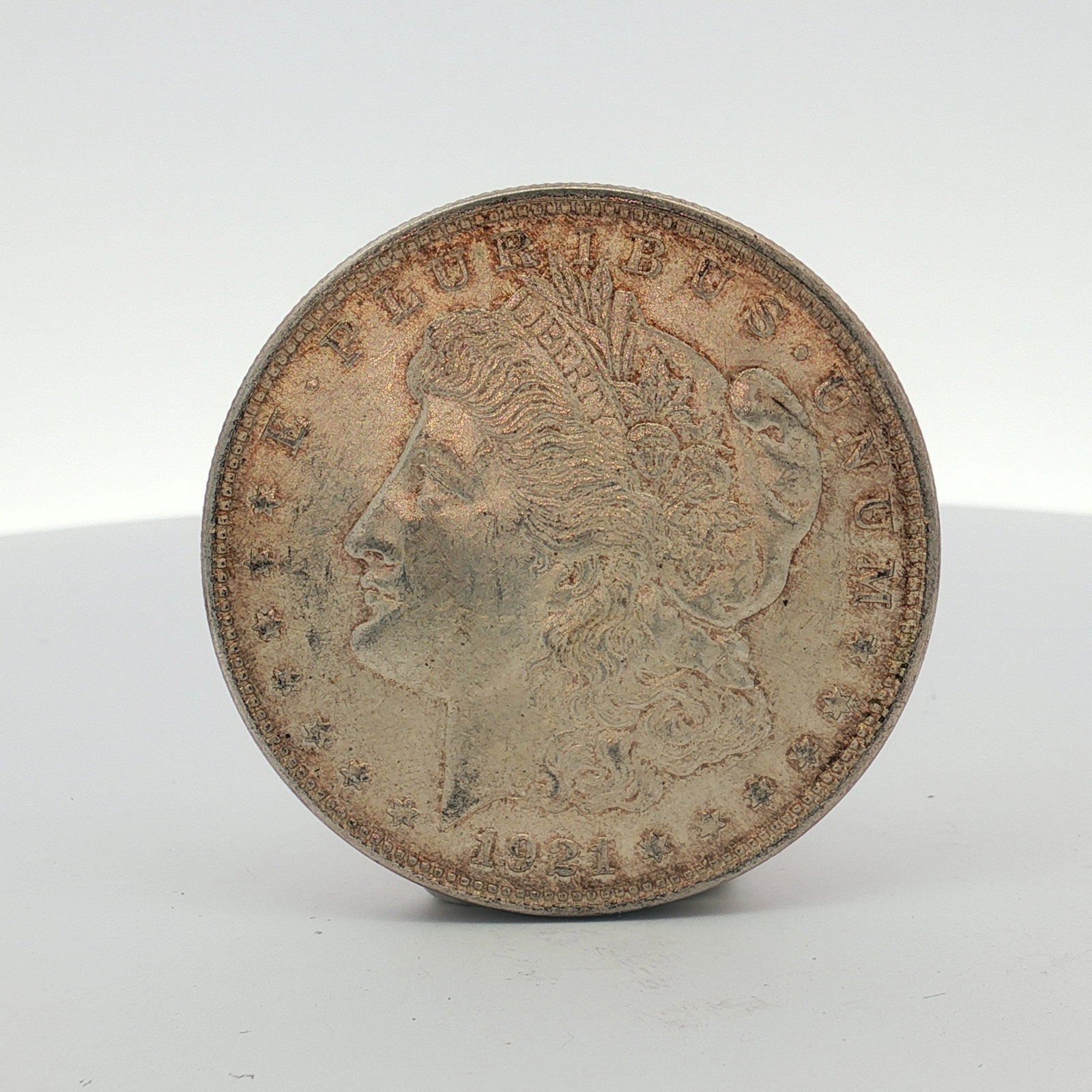 1921 US Morgan Silver Dollar Coin Circulated: This US Morgan silver dollar is dated 1921 and was struck at the Philadelphia mint. The coin is composed of 90% silver and 10% copper with a fineness of .900. It features the standard Morgan dollar de
