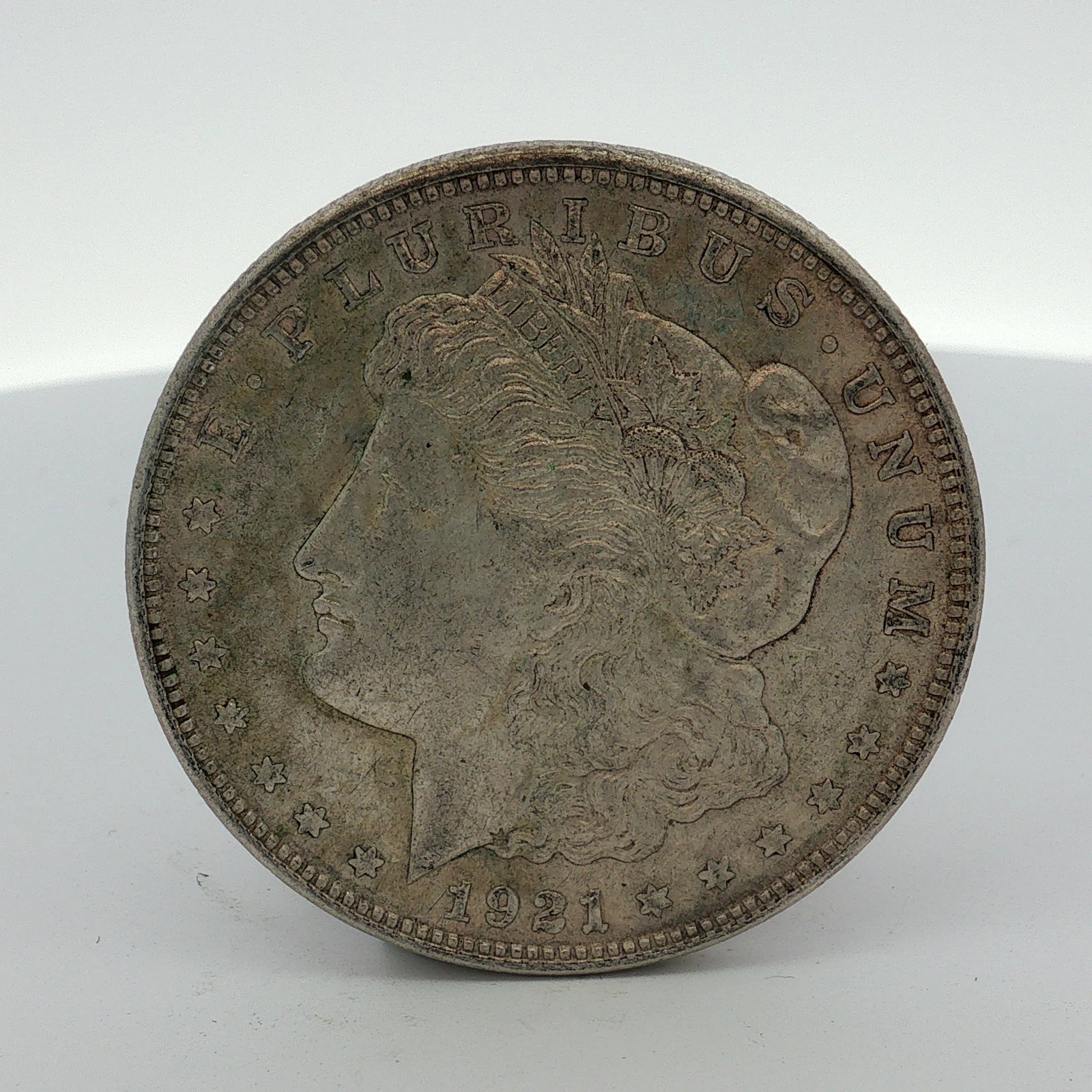1921 US One Dollar Morgan Silver Dollar, Circulated: US 1921 Morgan dollar struck at the Philadelphia Mint. The coin is composed of 0.900 fine silver and 0.100 copper. The obverse features the Morgan dollar Liberty head design with the date 1921 and the