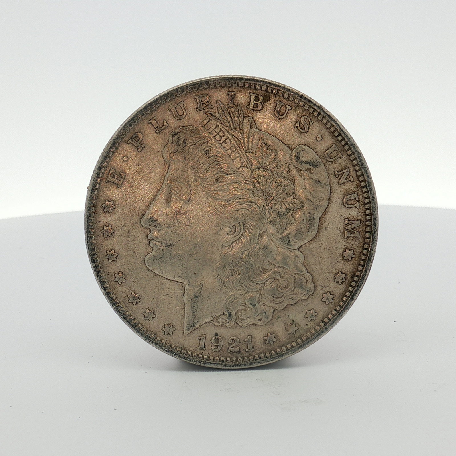 1921-D US Morgan Silver Dollar Coin Circulated: This US Morgan dollar was struck at the Denver Mint in 1921. The coin is composed of 90 percent silver and 10 percent copper with a fineness of .900 silver. The obverse features the Morgan design with