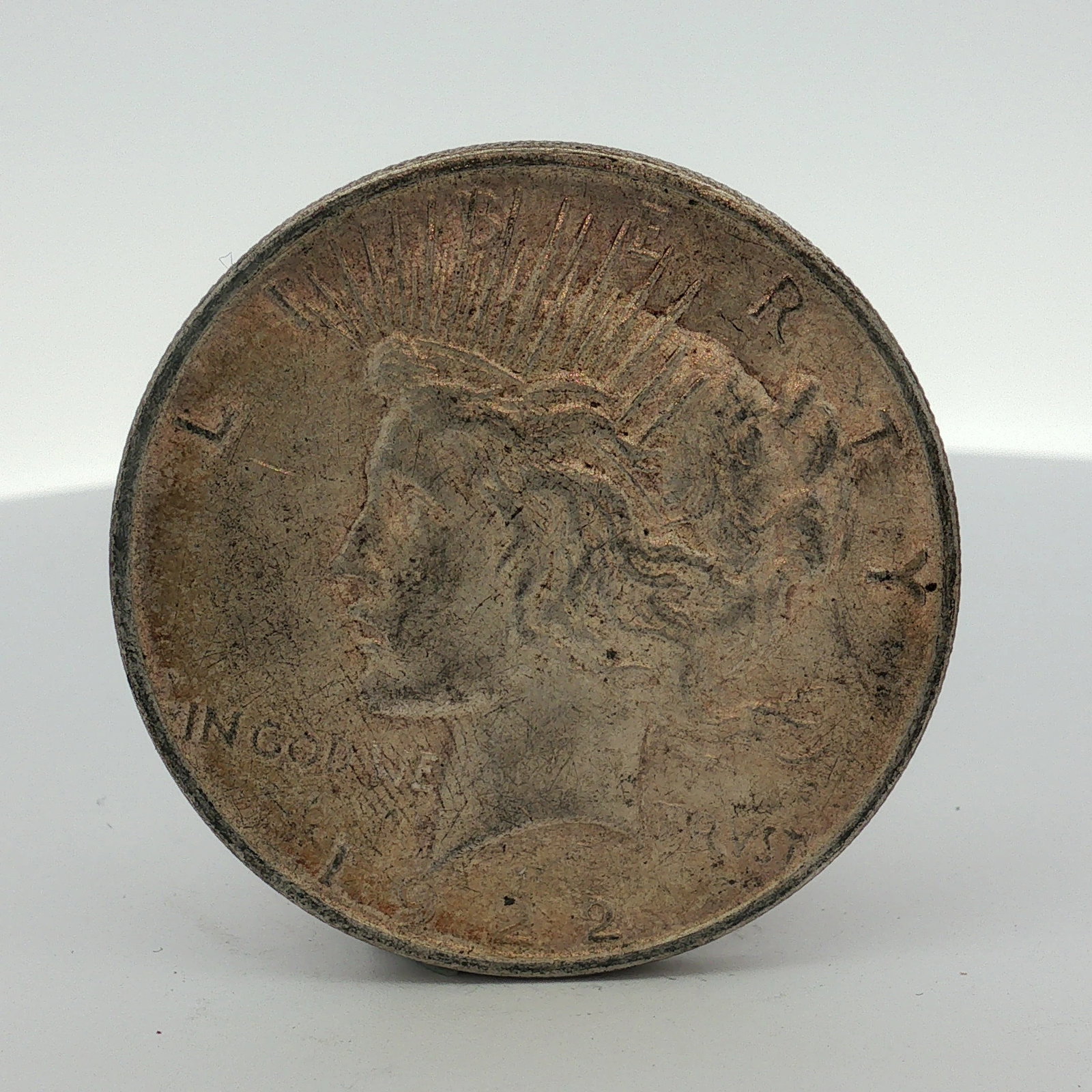 1922-D US One Dollar Peace Silver Dollar, Circulated: This US Peace dollar is dated 1922-D and was struck at the Denver Mint. The coin is composed of 90 percent silver and 10 percent copper. It features the standard Peace dollar design on both the obvers