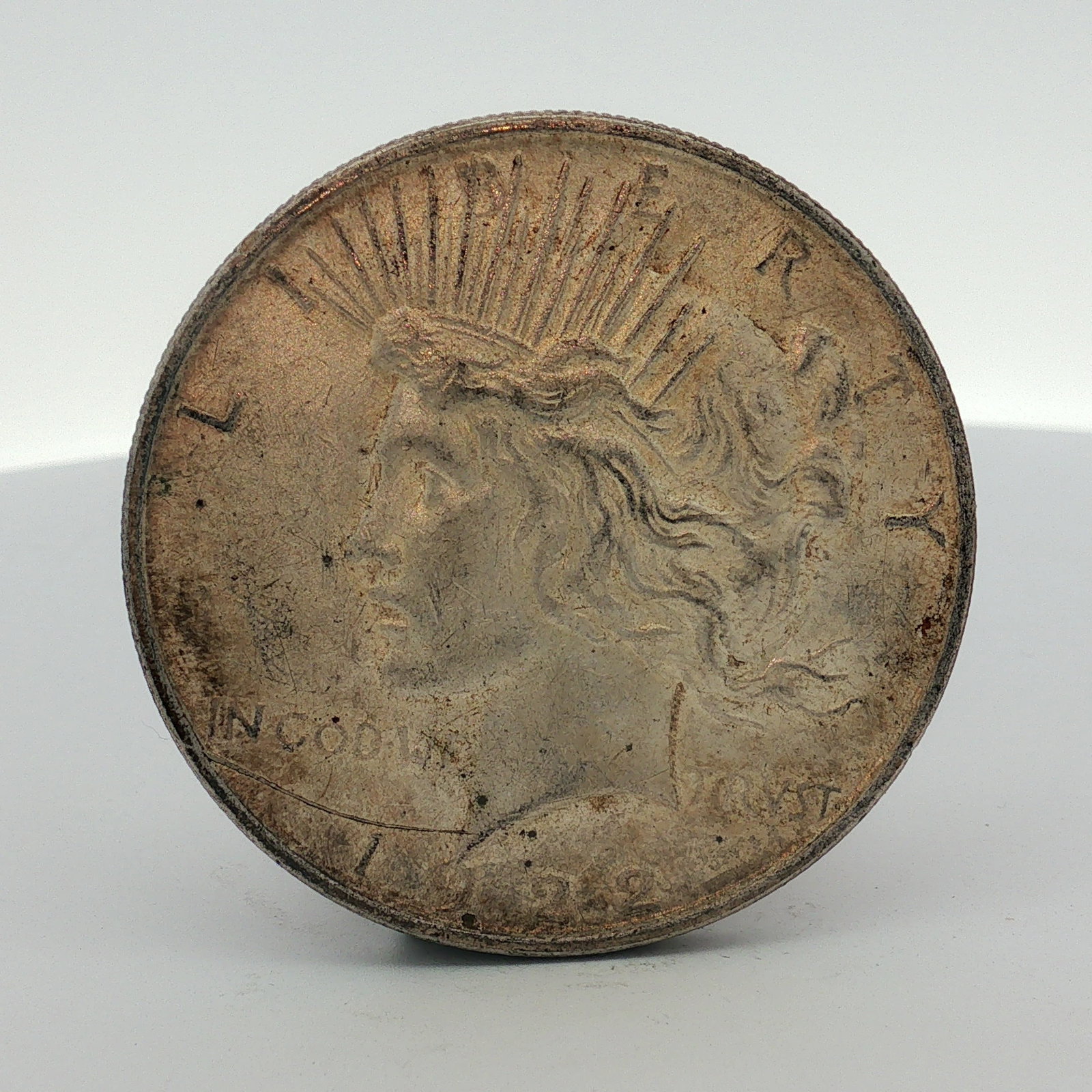1922-D US One Dollar Peace Silver Dollar, Circulated: This US Peace dollar was produced at the Denver Mint in 1922. The coin is a low relief variety struck in 0.900 fine silver. It features the standard Peace dollar obverse and reverse design types. A D 