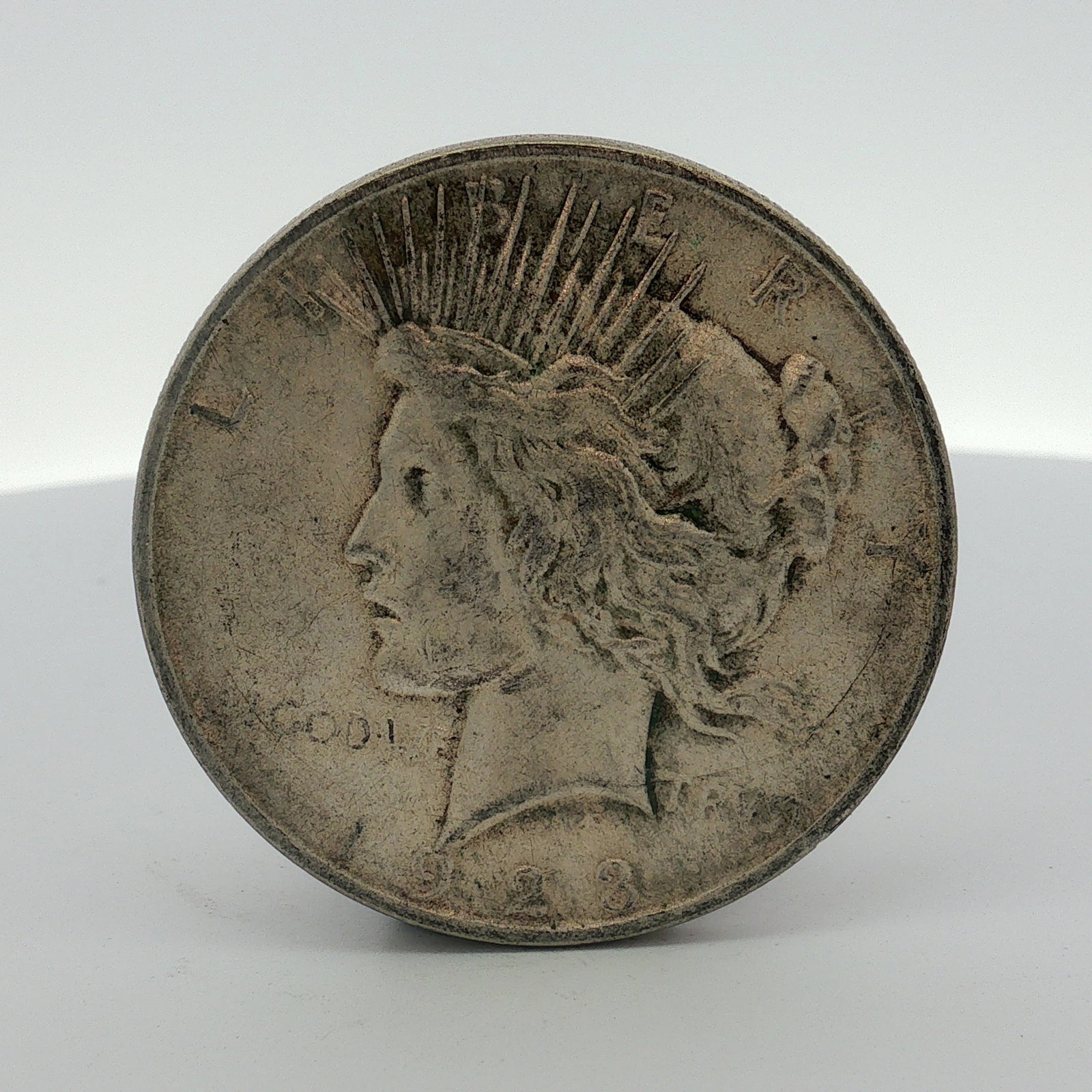 1923-D US One Dollar Peace Silver Dollar, Circulated: This US 1923 Peace silver dollar was struck at the Denver Mint. The coin is composed of 90% silver and 10% copper. The obverse features the Liberty head design with a radiate crown, while the reverse 
