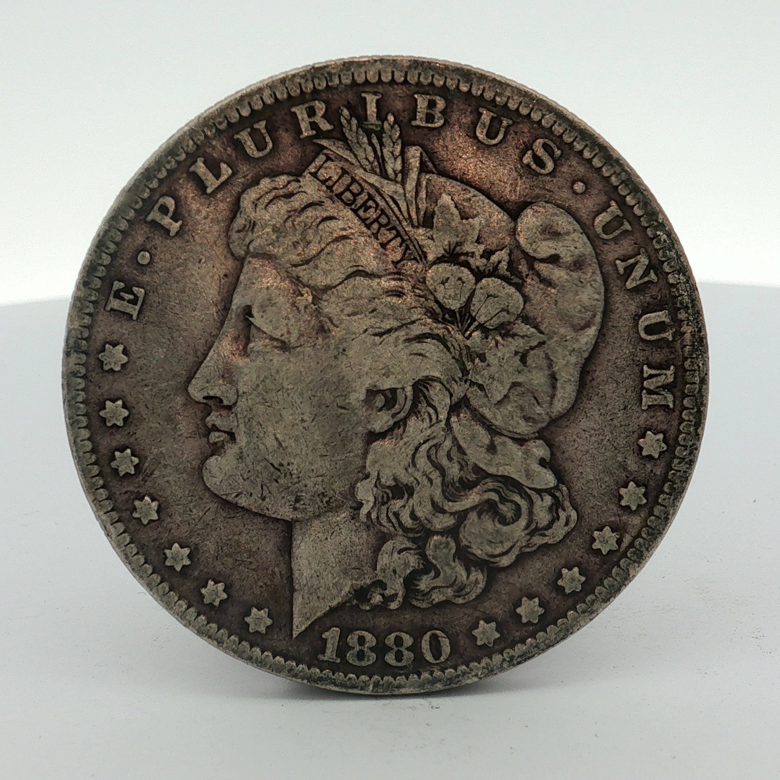 US 1880-O Morgan Silver Dollar: This US 1880-O Morgan silver dollar was struck at the New Orleans Mint, as indicated by the O mint mark on the reverse. The coin is composed of 90% silver and 10% copper. It features the standard Morg