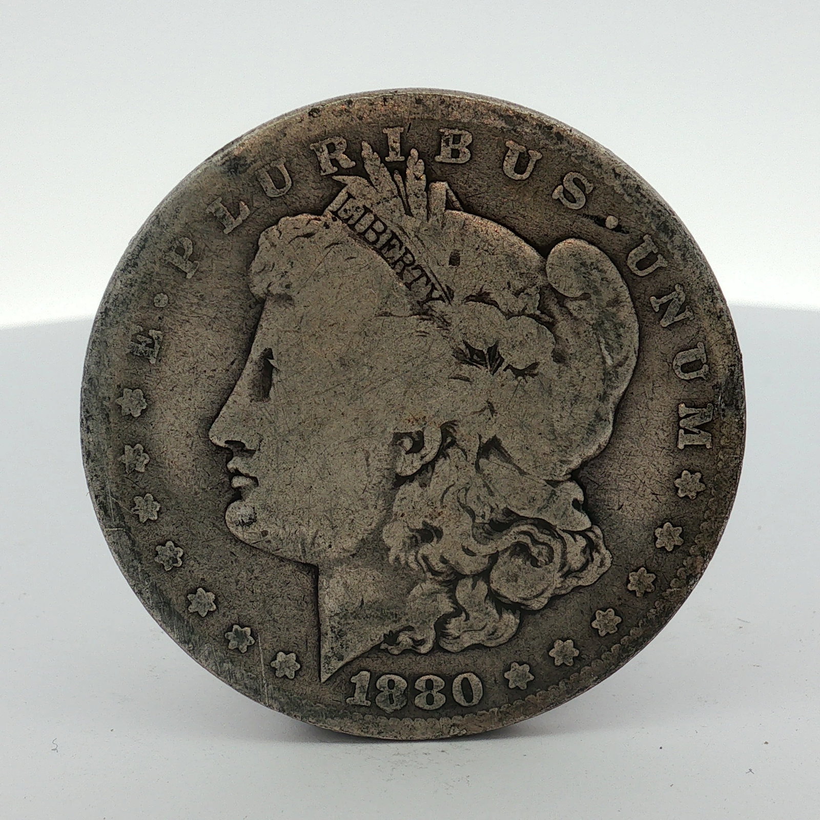 US 1880-O Morgan Silver Dollar: This US 1880-O Morgan silver dollar was produced at the New Orleans Mint. The coin features the Morgan dollar design on the obverse with the date 1880 and the legend E PLURIBUS UNUM. The reverse displ