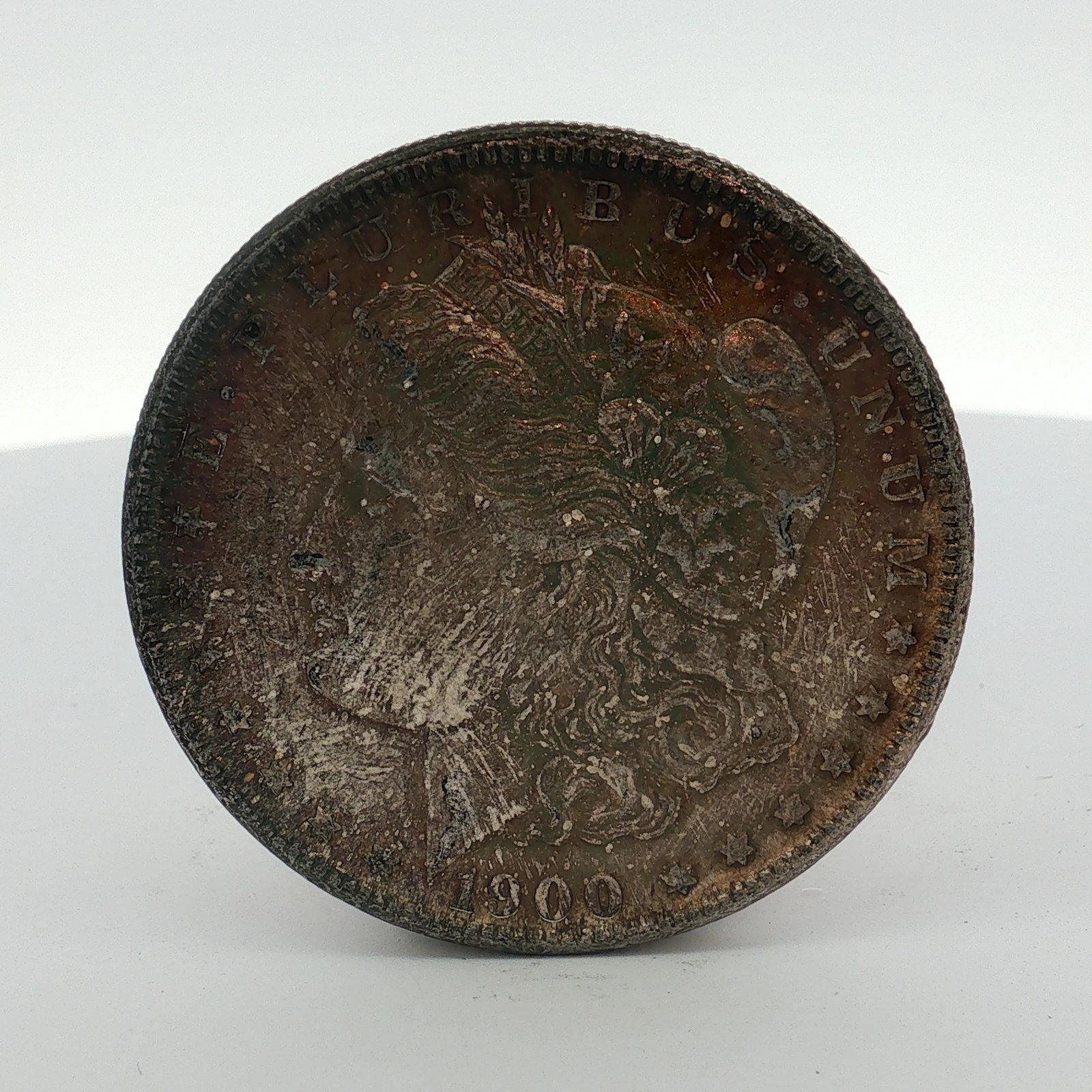 US 1900-O Morgan Silver Dollar: This coin is composed of .900 silver and .100 copper. The obverse features the Liberty head design with the date 1900 and the legend E PLURIBUS UNUM. The reverse displays the heraldic eagle design, th