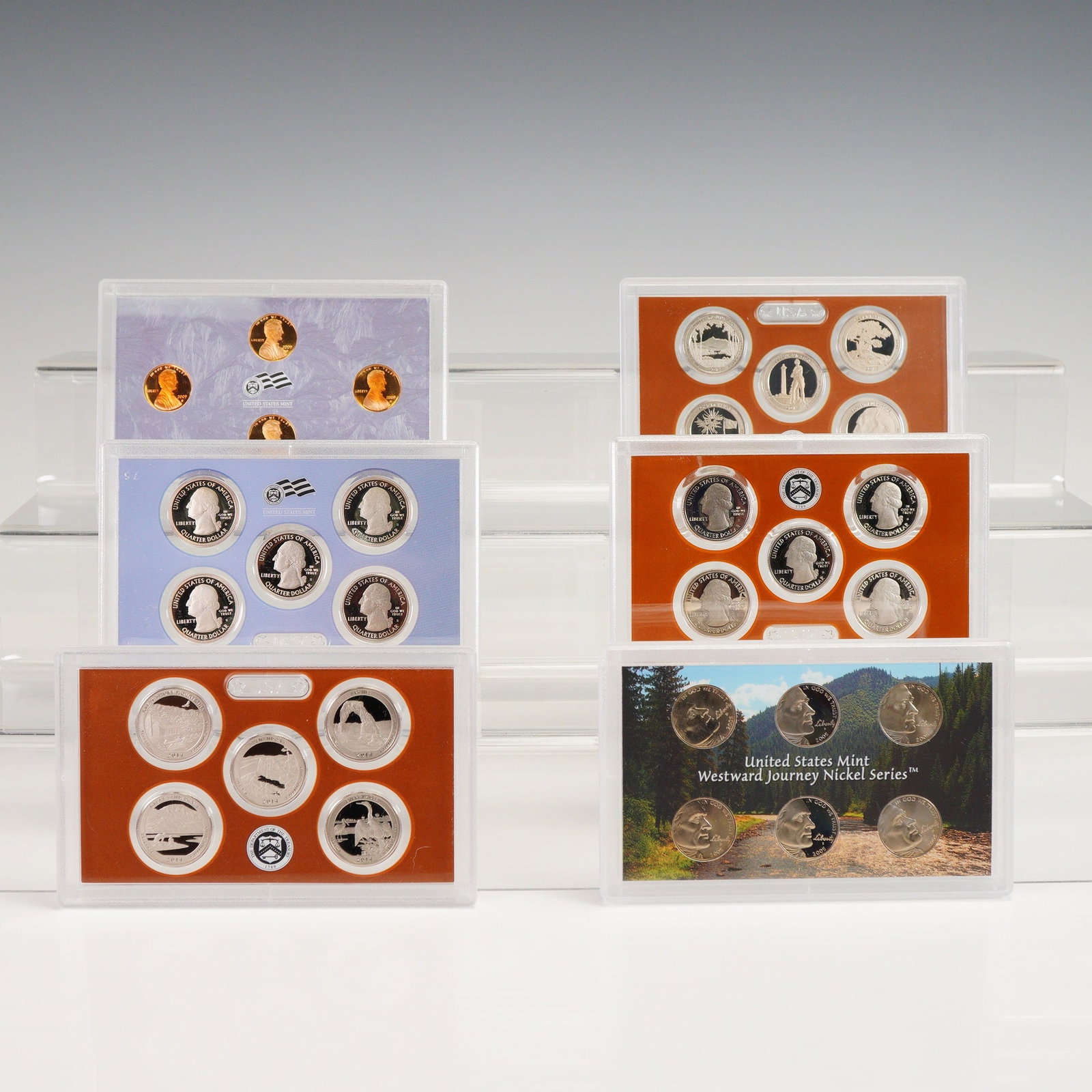 6pc 2005, 2009, 2010, 2013-15 Nickels, Lincoln & Quarters Proof Sets: Proof Sets featuring nickels, Lincoln cents, and America the Beautiful quarters spanning multiple years, all housed in original Mint-issued hard plastic display cases. The lot contains 2005 Westward J