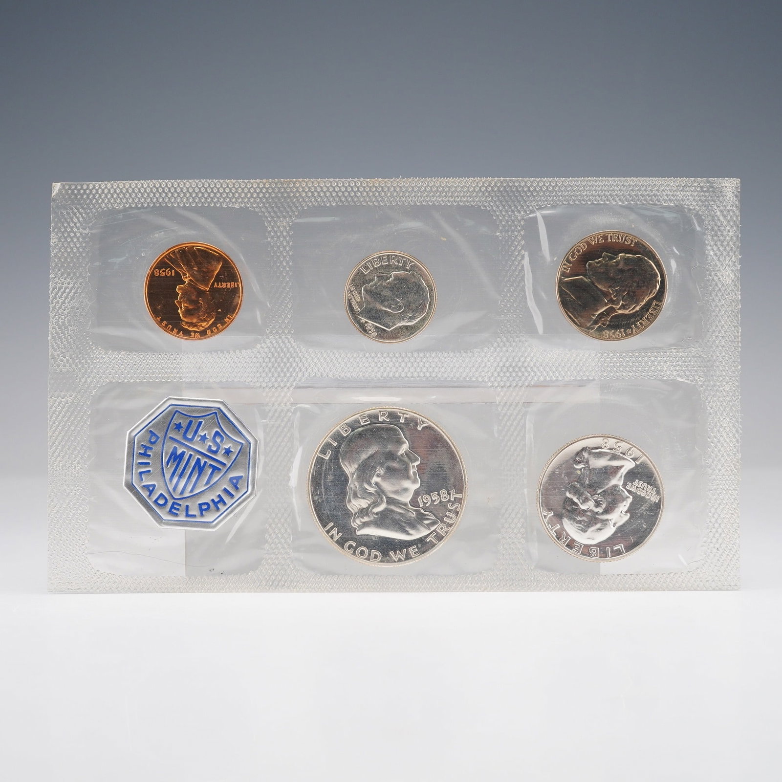1958 U.S. Mint Coin Proof Set: Coin set is presented in its original sealed cellophane packaging. The set includes five coins: a Lincoln Cent with obverse inscriptions Liberty, In God We Trust, 1958 and reverse United States of Ame
