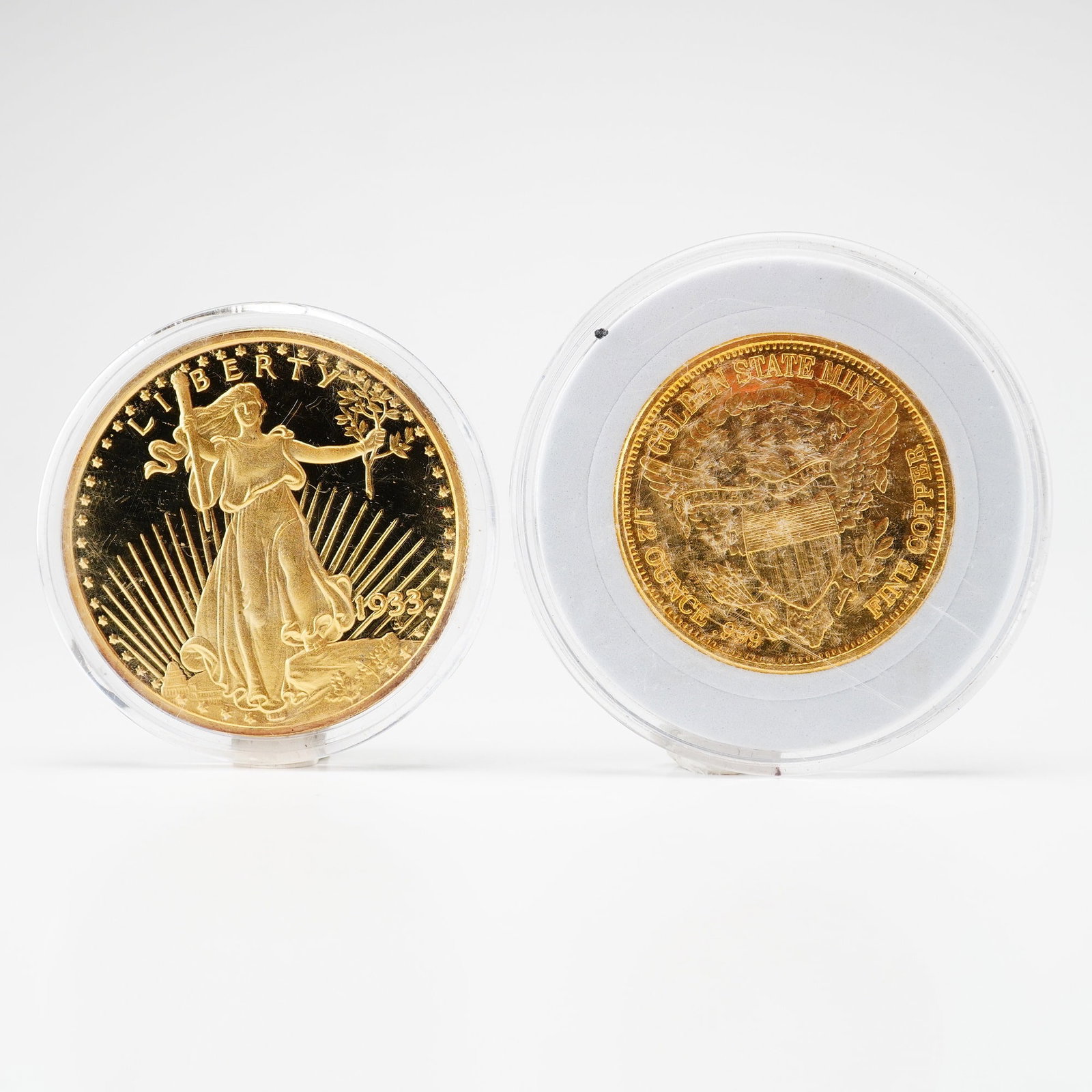 2pc Commemorative Rounds, 1933 Double Eagle Silver Bullion with Gold-Plating and Golden State Mint: This lot features 2 coins presented as gold-toned commemorative rounds in individual plastic capsules. The first item is a tribute replica of the 1933 Saint-Gaudens Double Eagle which is a silver bull