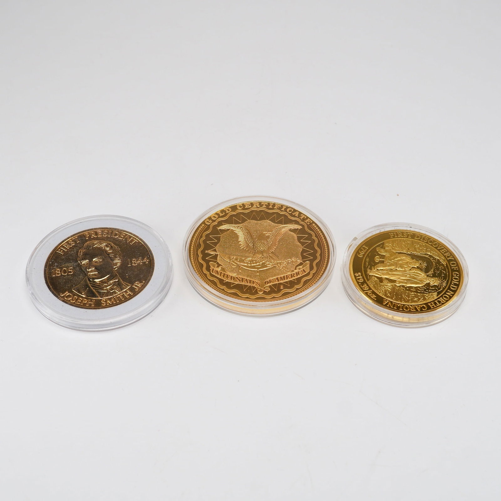 Three Commemorative Coins by American Mint Featuring Abraham Lincoln and Joseph Smith Jr.: Each item is housed in a clear protective plastic capsule. The collection includes a Joseph Smith Jr. medal marked First President 1805-1844 with a reverse depicting the Salt Lake Temple of the Church