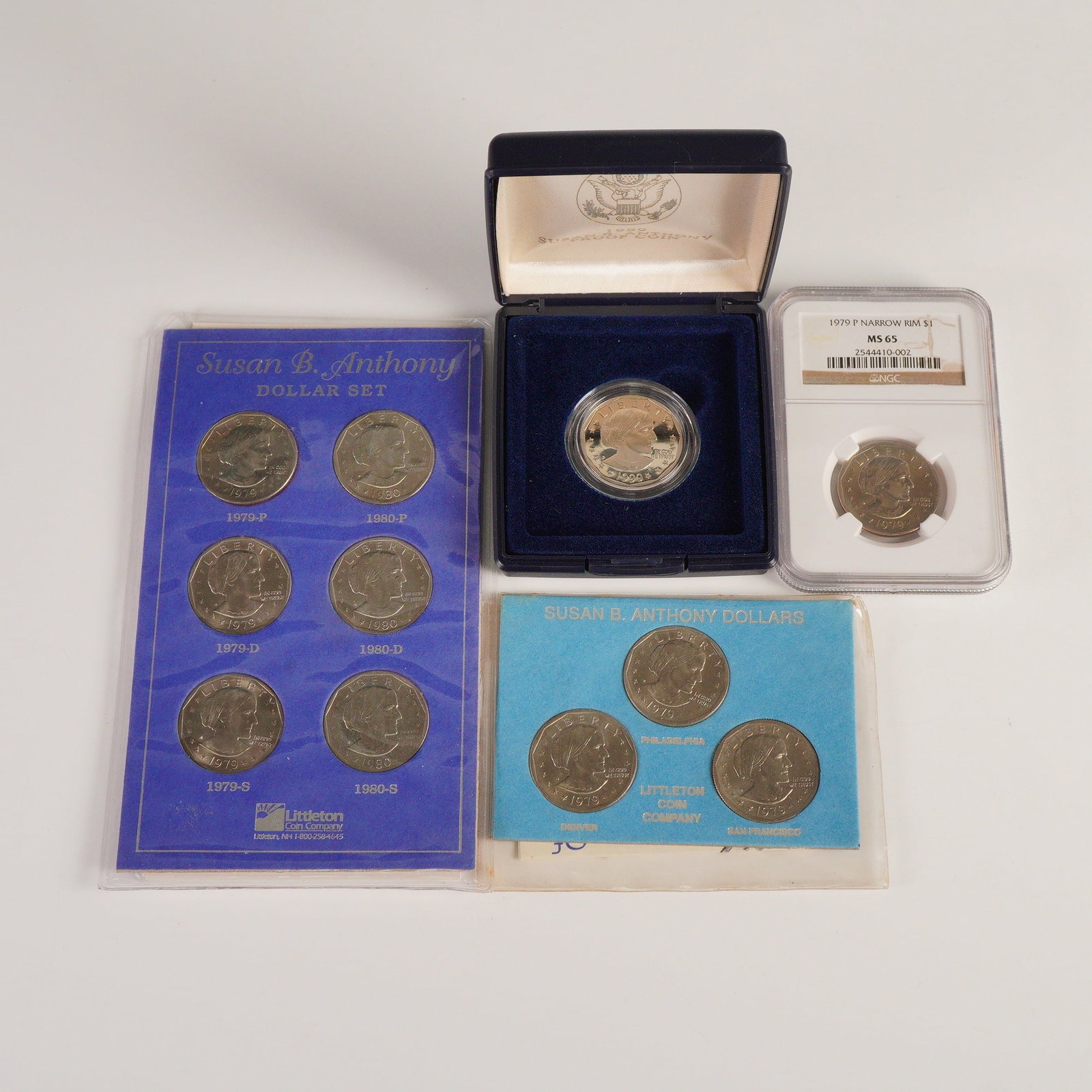 4pc 1979 & 1999 U.S. Susan B. Anthony One Dollar Coins: Includes a 1979-P narrow rim NGC graded MS65, a set of three 1979 first year mint including a Philadelphia, a Denver, and a San Francisco example. Also included is a Littleton Coin Company Susan B. An