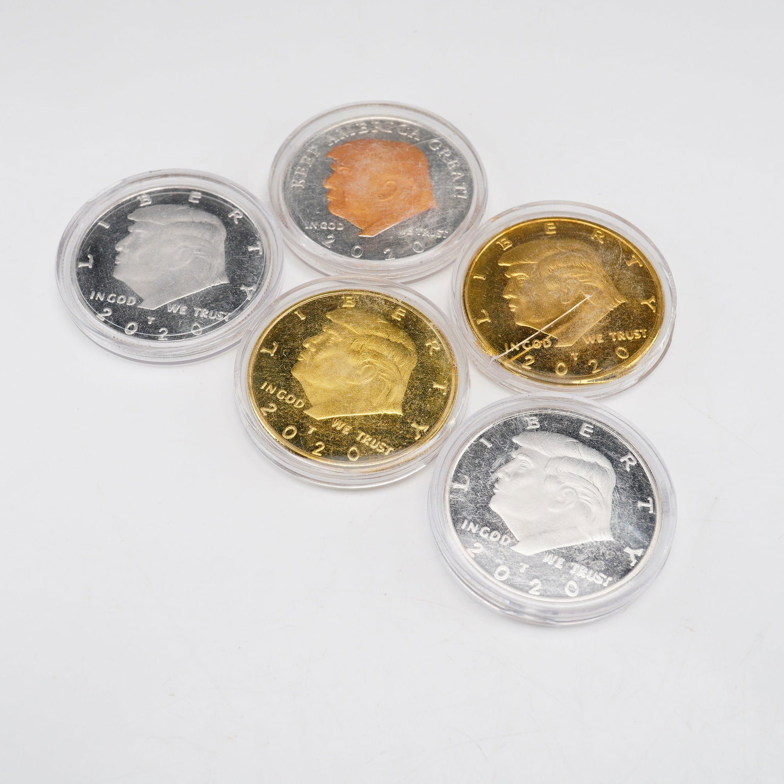 Lot of Five 2020 US Donald Trump Commemorative Medallions: This set consists of five Donald Trump dollar coins, which are privately struck commemorative rounds dated 2020. The collection features two gold-plated rounds, two silver-plated rounds, and one two-t