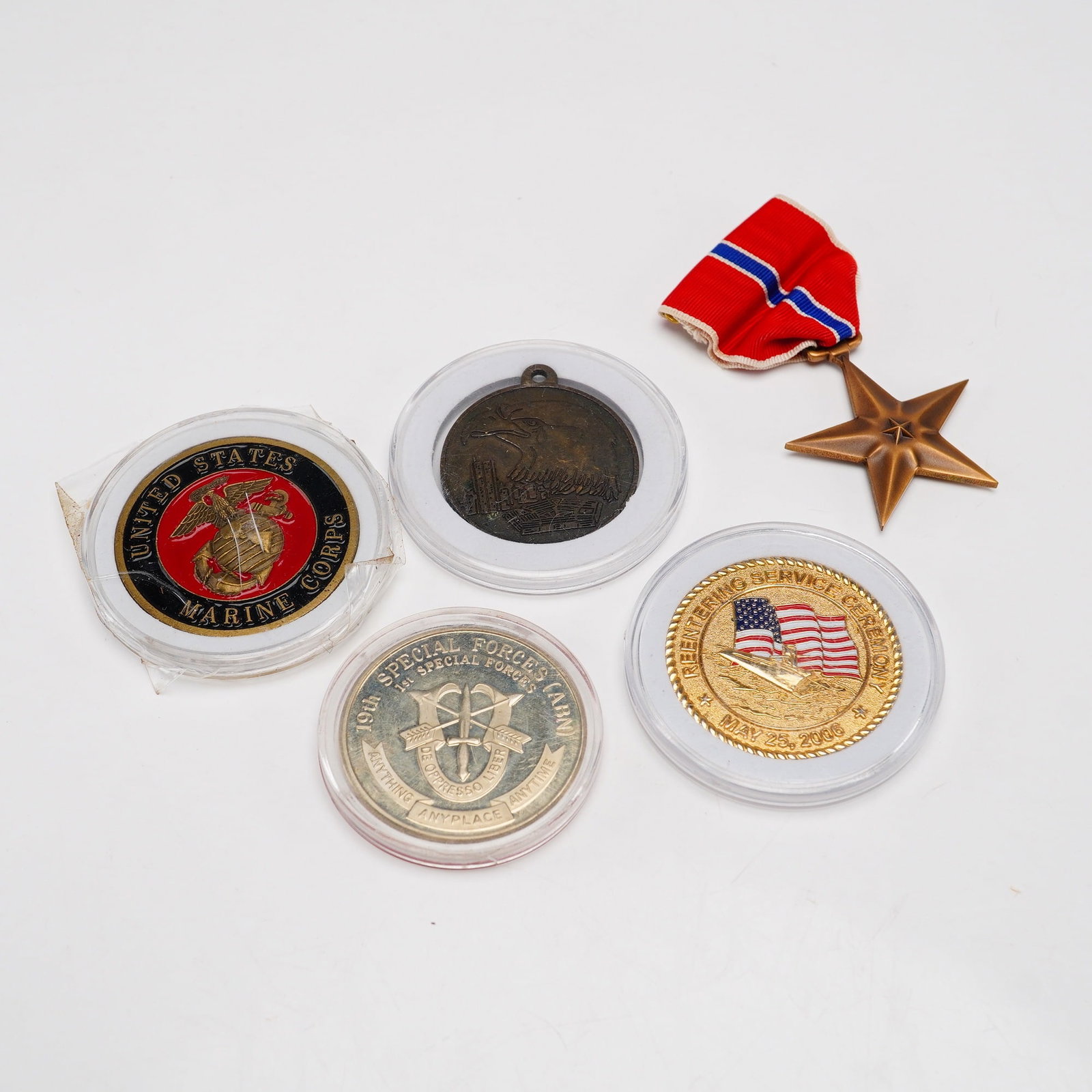 5pc Collection of United States Military Medals and Challenge Coins Housed in Protective Cases: This 5pc collection of United States military memorabilia includes one service decoration and four commemorative challenge coins and medals. The collection features a full-size Bronze Star Medal, whic