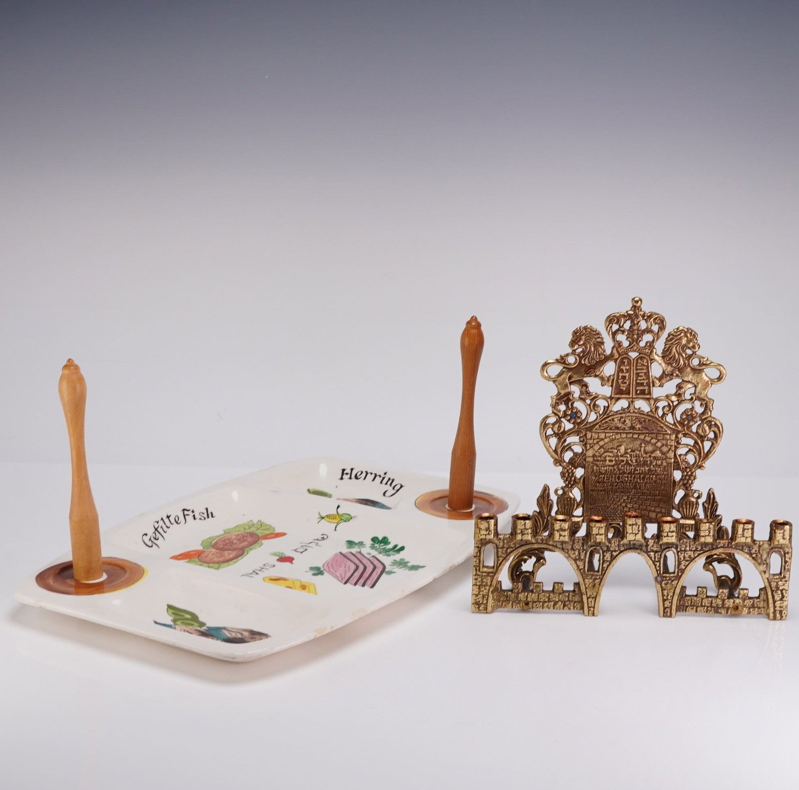 2pc Judaica Hanukkah Menorah and Platter: A two-piece collection of 20th-century Judaica comprising a cast brass Hanukkah menorah and a decorated ceramic serving platter. The bench-style Hanukkiah is constructed of cast brass with a gold-tone