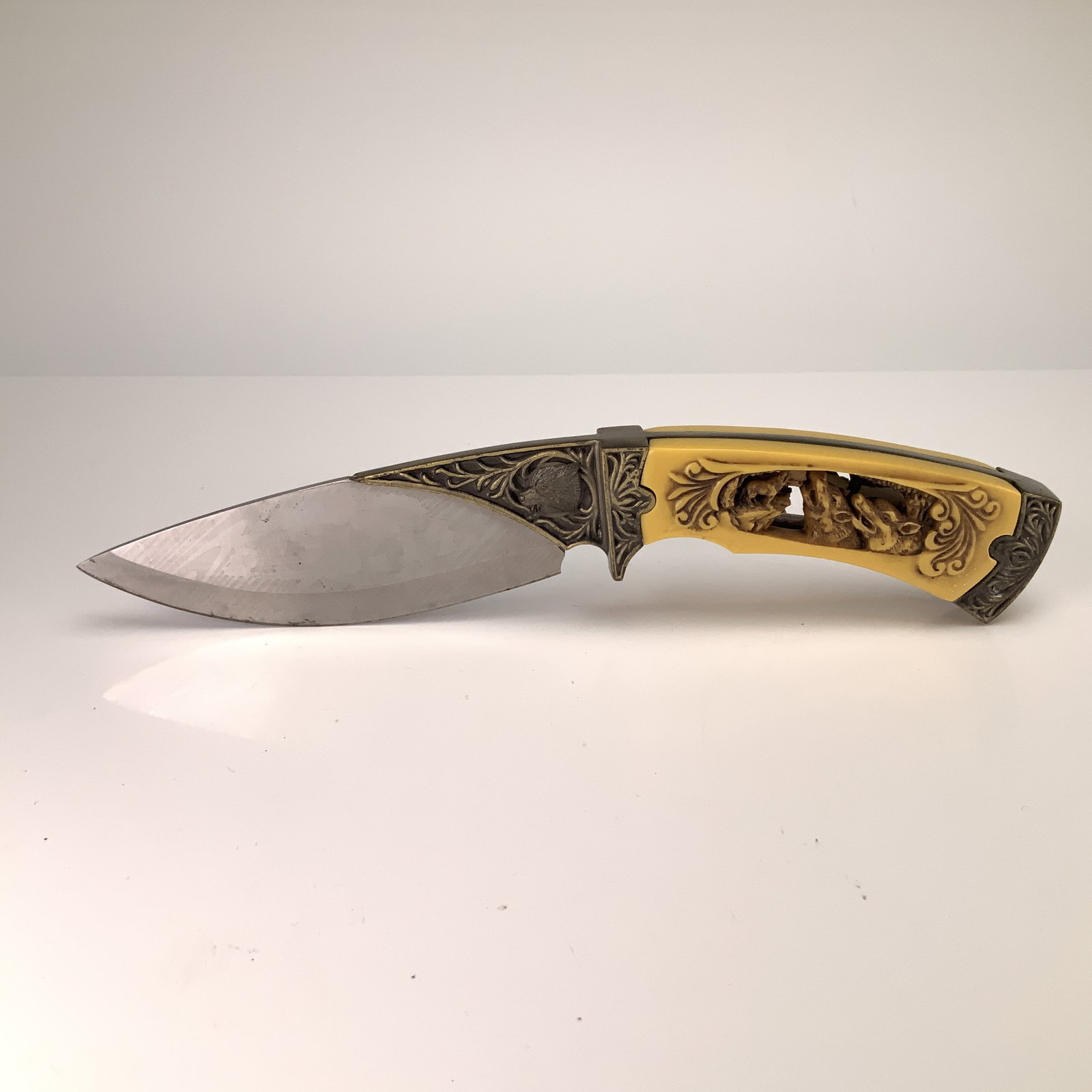 Wildlife Collection Resin Carved Handle Knife w/ Etched Blade: This Wildlife Collection fixed blade knife features a stainless steel blade with a decorative etched scene. The etching depicts two wolves in a mountainous wilderness under a moon, set against a backg
