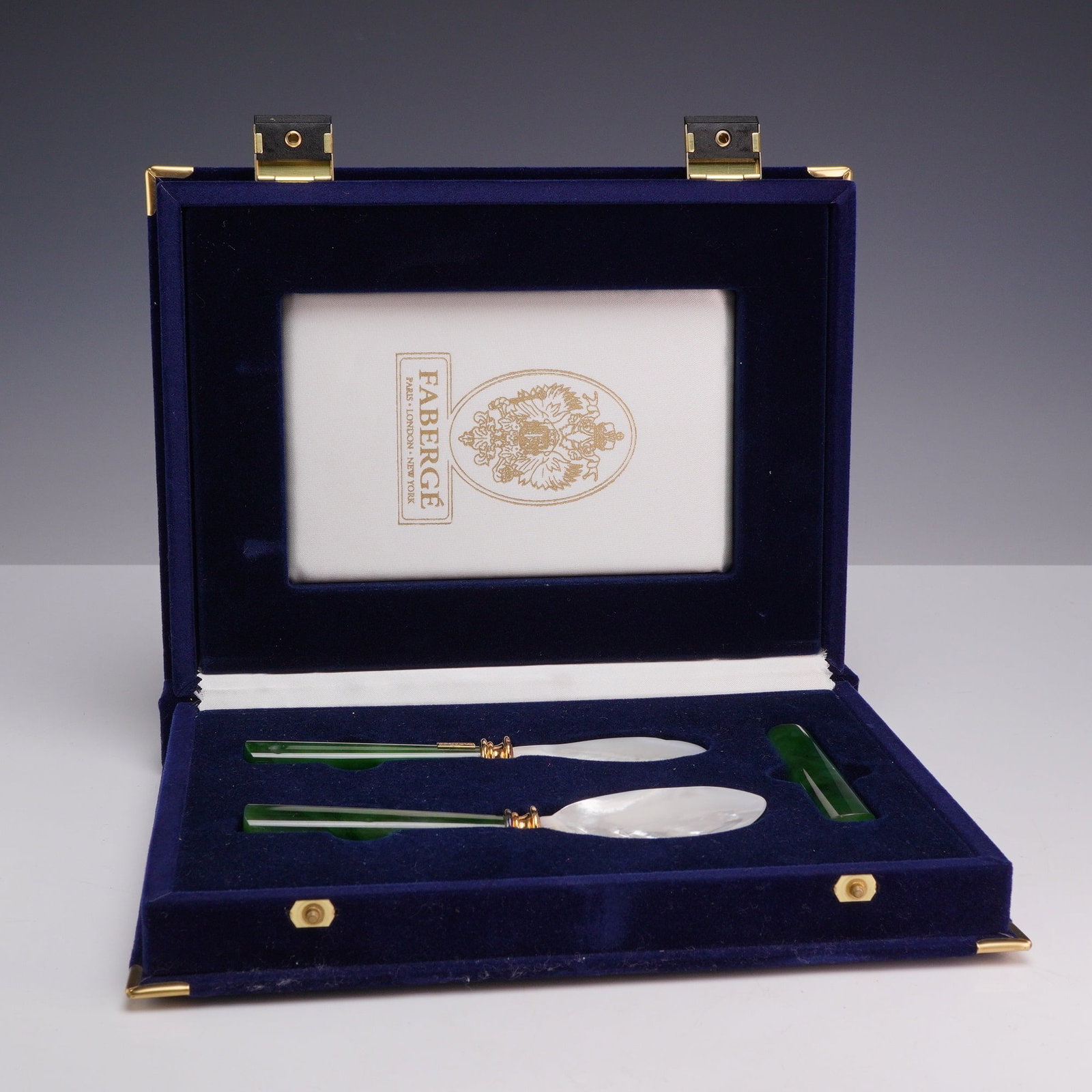 Faberge Three Piece Mother of Pearl and Nephrite Jade Caviar Service Set in Original Box: A three piece Faberge caviar service set comprising a serving spoon, a spreader, and an additional matching nephrite jade handle or rest. The serving spoon and spreader feature carved iridescent mothe