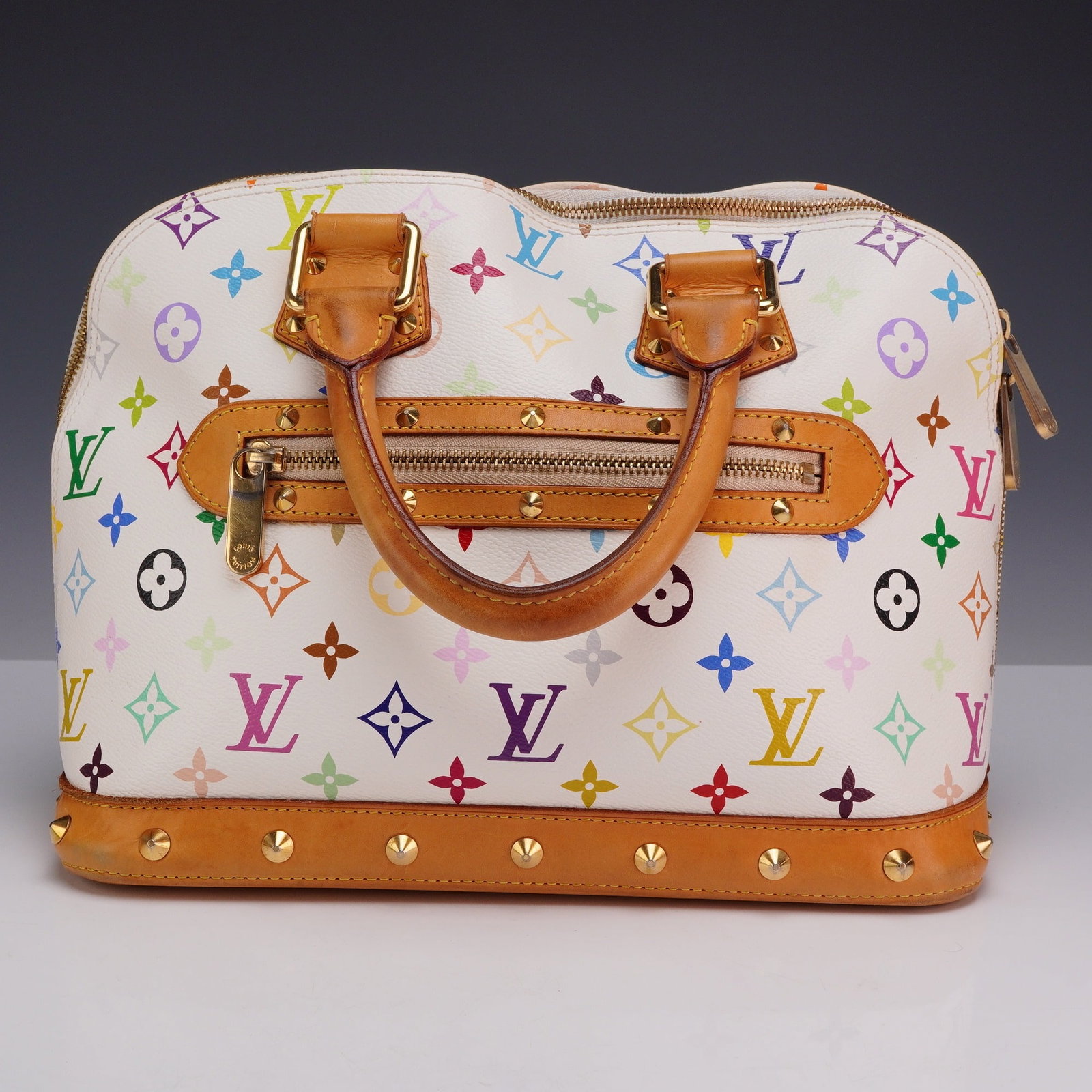 Louis Vuitton x Takashi Murakami Monogram Multicolore Alma PM Handbag: This Louis Vuitton Alma PM is from the Monogram Multicolore collection, a collaboration between the fashion house and Japanese artist Takashi Murakami. The bag is constructed from white coated canvas 