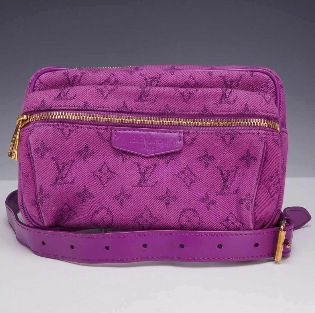 Louis Vuitton Purple Monogram Denim Outdoor Bumbag Waist Bag: A Louis Vuitton Outdoor Bumbag crafted from purple Monogram Denim with tonal leather trim and an adjustable leather waist strap. The bag features a rectangular silhouette with two separate zippered co
