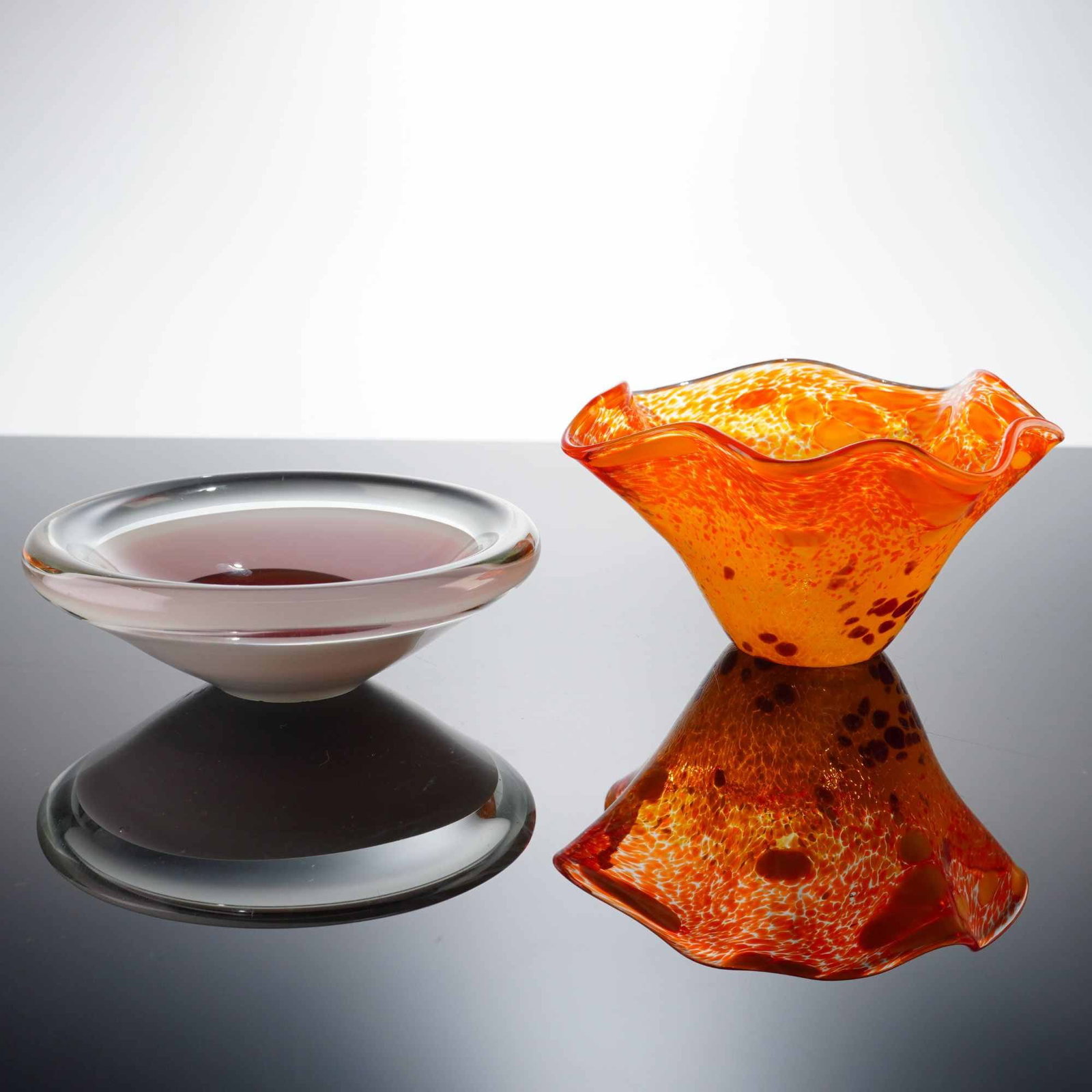2pc Contemporary Art Glass Bowls Including Weisbach: The first piece is a heavy, thick-walled bowl executed in the sommerso technique. It features a deep cranberry red center well encased in a translucent lavender layer, which is further encased in a he
