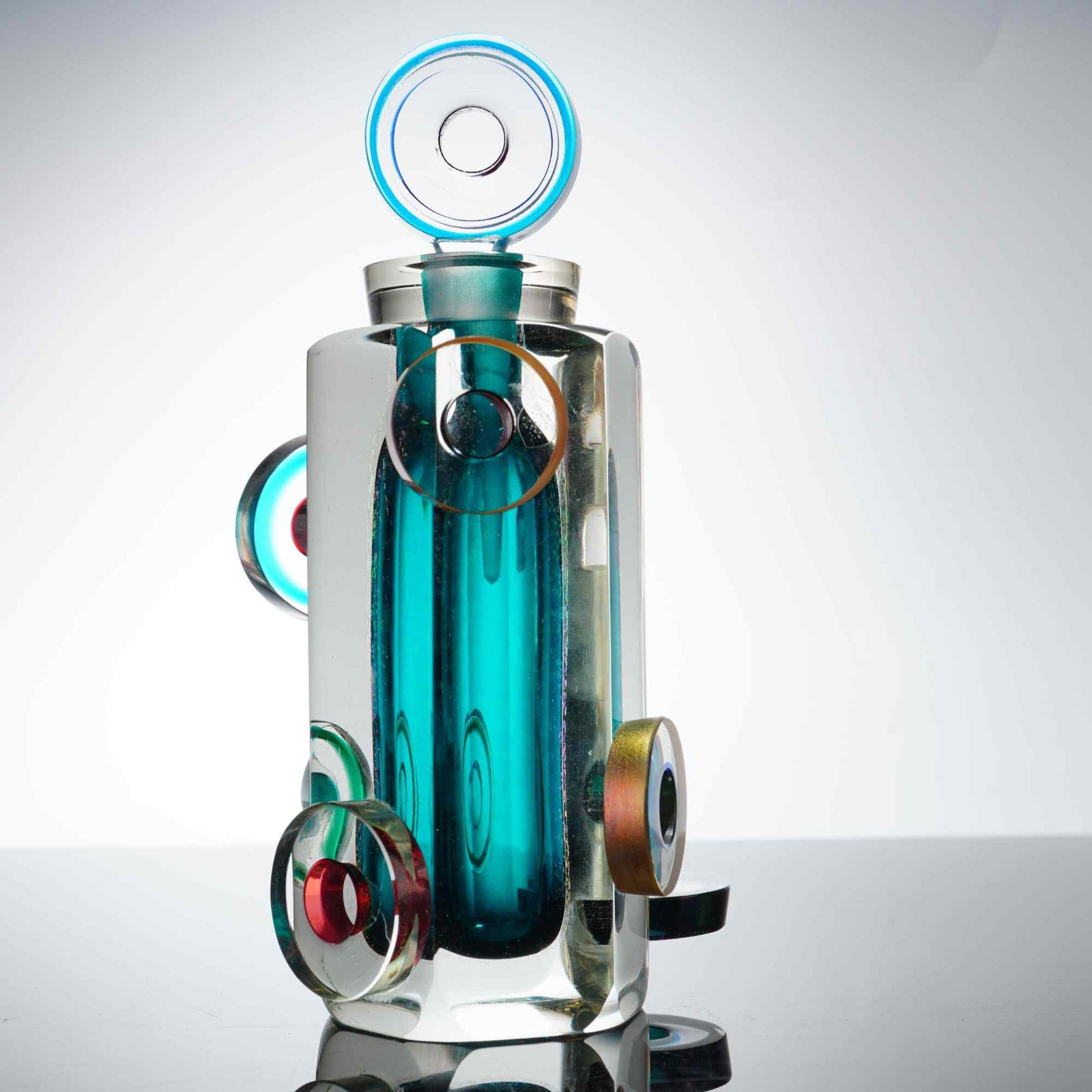 Correia Art Glass Perfume Bottle and Stopper: This limited-edition studio art glass perfume bottle and matching stopper produced by Correia Art Glass. The piece is constructed from heavy, clear faceted glass featuring a submerged teal-blue intern