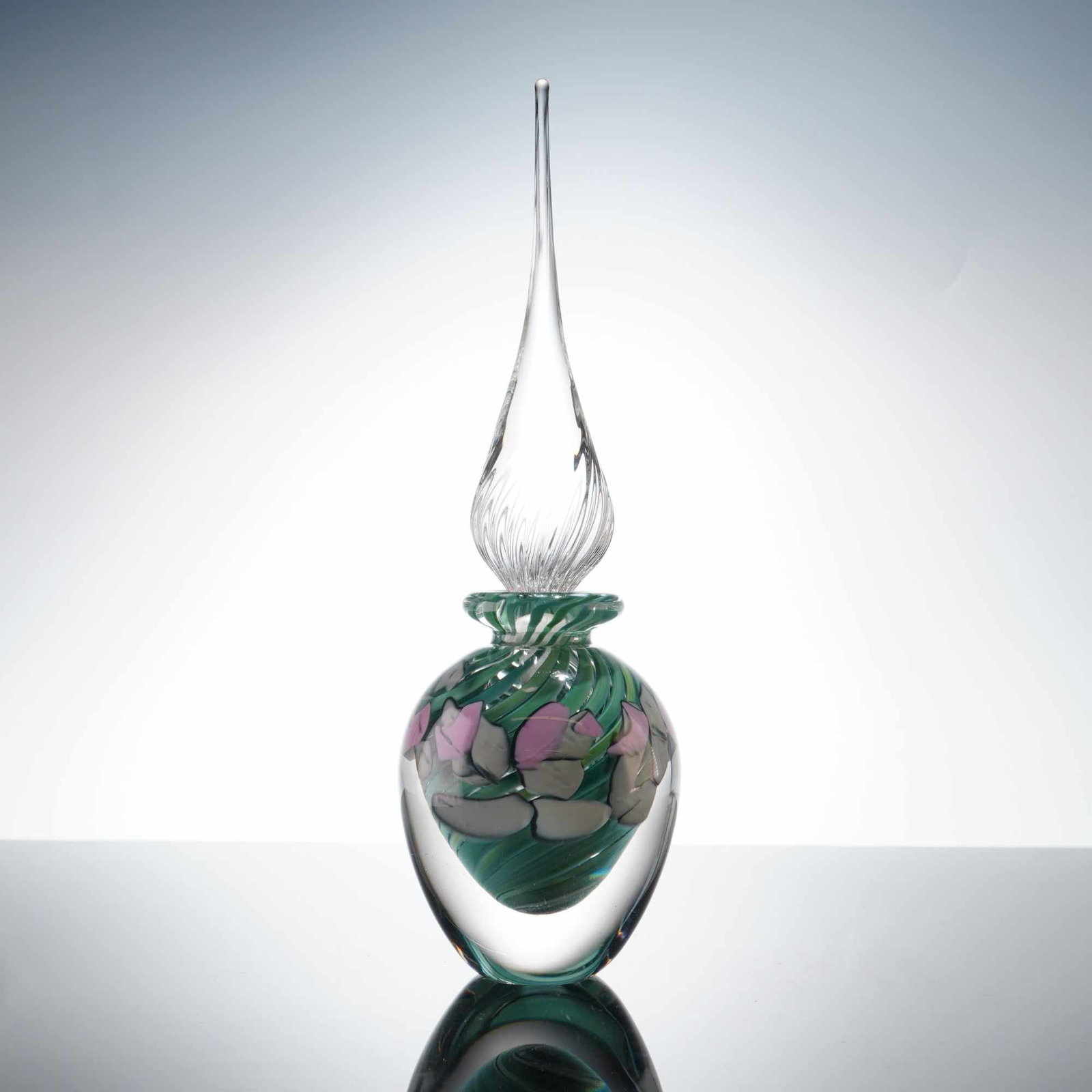 Studio Art Glass Swirled Green and Pink Perfume Bottle and Stopper: This hand-blown studio art glass perfume bottle and stopper features a globular body constructed with a thick clear glass casing over a core of swirled emerald and mint green glass. The interior is fu