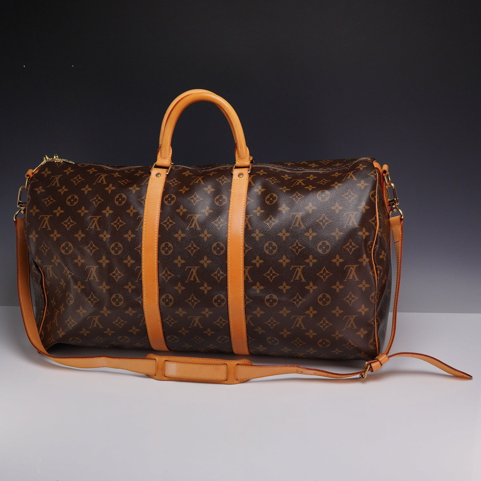 Louis Vuitton Monogram Keepall Bandouliere 60 Travel Bag: Louis Vuitton travel duffle bag in the Monogram Keepall Bandouliere 60 style. This piece is crafted from signature brown Monogram coated canvas with Vachetta leather trim and dual rolled handles. It f