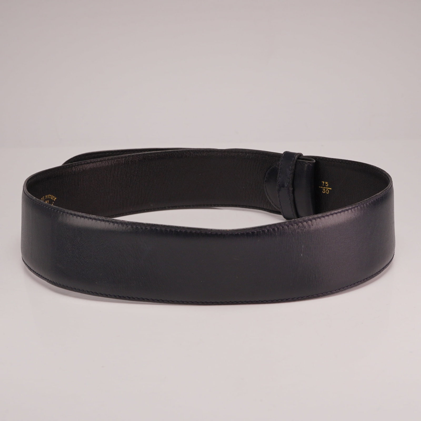 Gucci Made in Italy Leather Belt in Dark Blue: This authentic Gucci all leather belt is dark blue in color and was made in Italy. The wide leather strap features a smooth finish and a tapered end with three pre-punched sizing holes. It includes a 