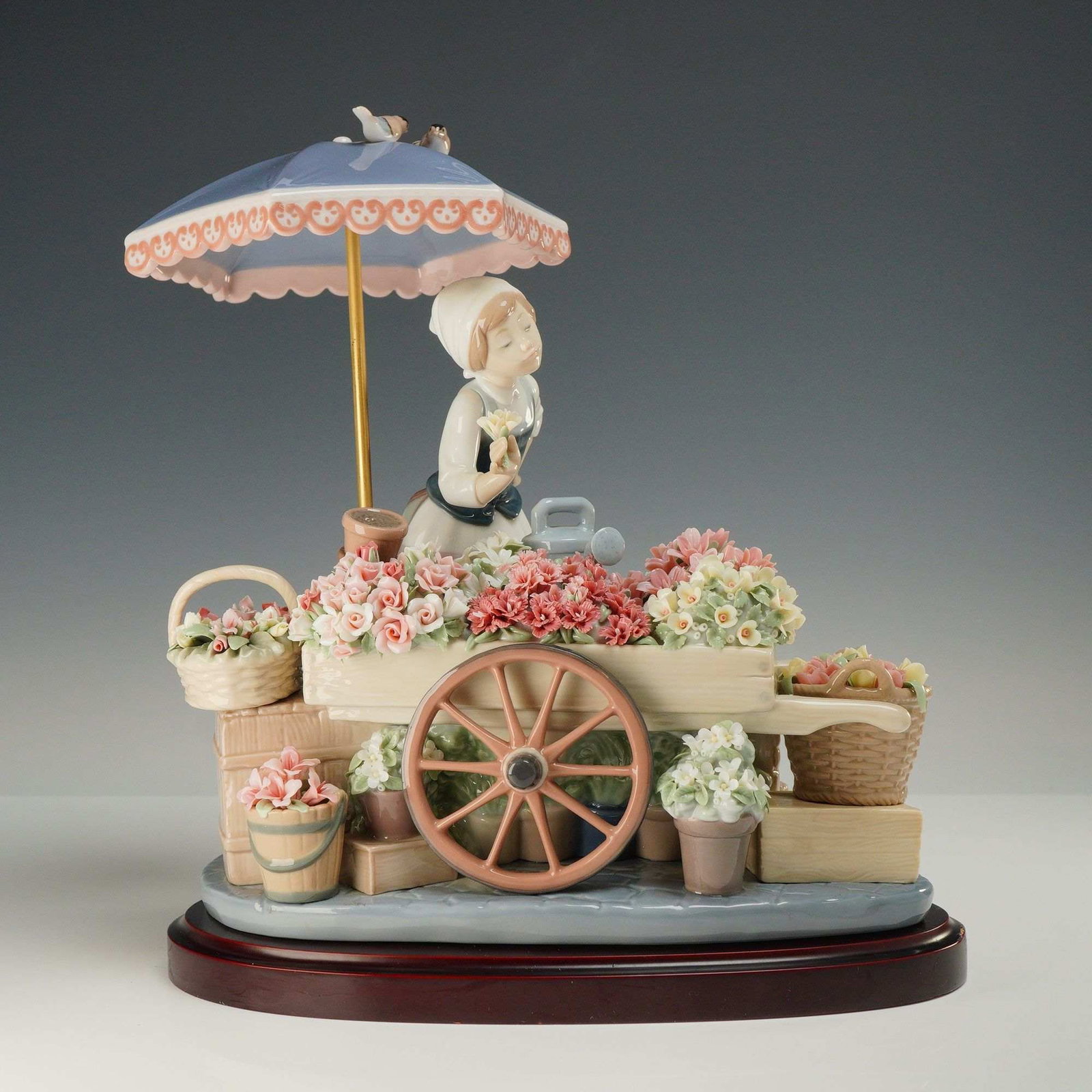 Lladro Flowers of the Season Porcelain Figurine with Base 1001454: A Lladro glazed porcelain figurine titled Flowers of the Season, model number 01001454, originally sculpted by Jose Puche. The composition features a young woman in traditional European attire standin