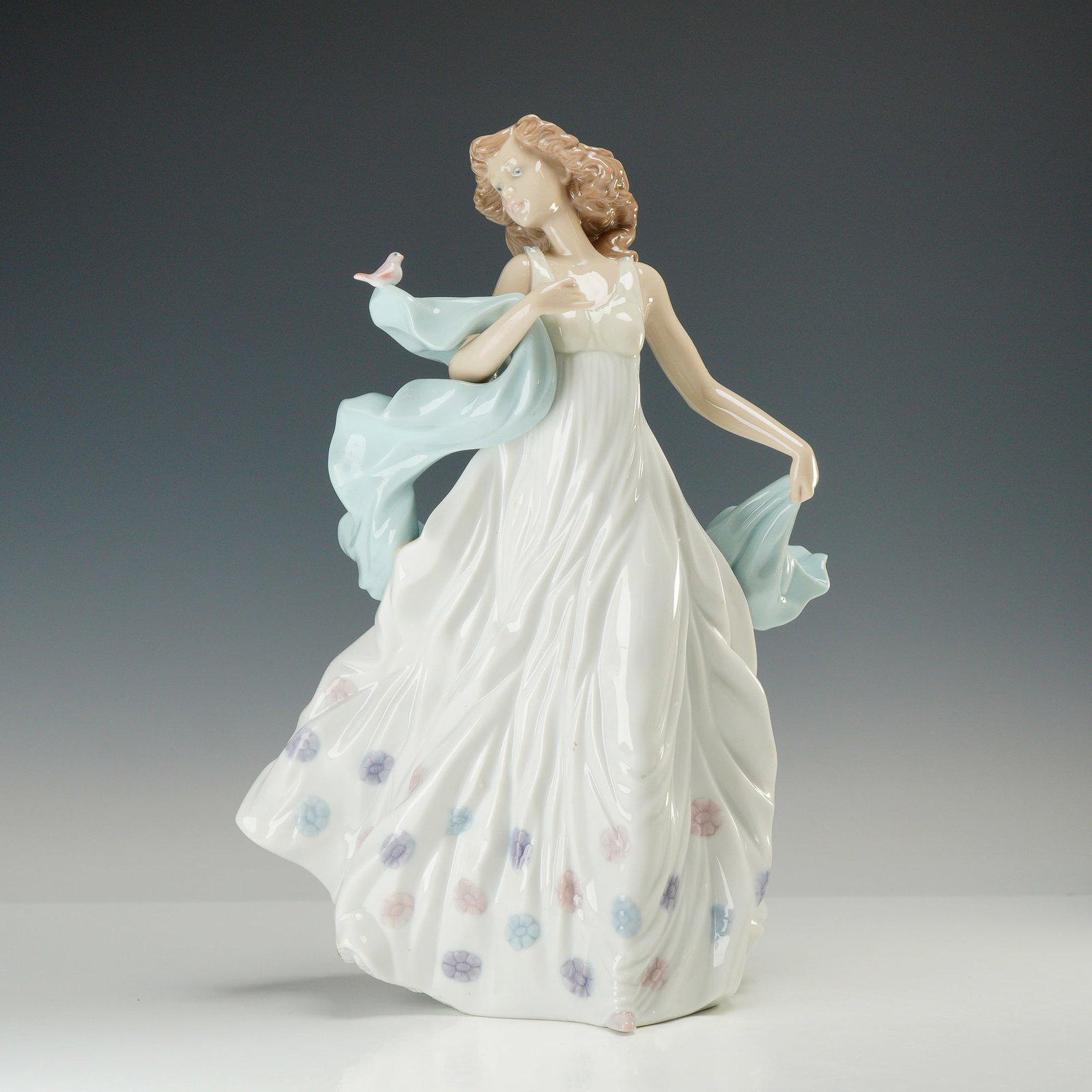 Lladro Porcelain Figurine Summer Serenade 01006193: This glazed porcelain figurine manufactured by the Lladro factory in Valencia, Spain. The piece depicts a young woman with auburn hair dressed in a sleeveless white gown featuring a subtle floral patt