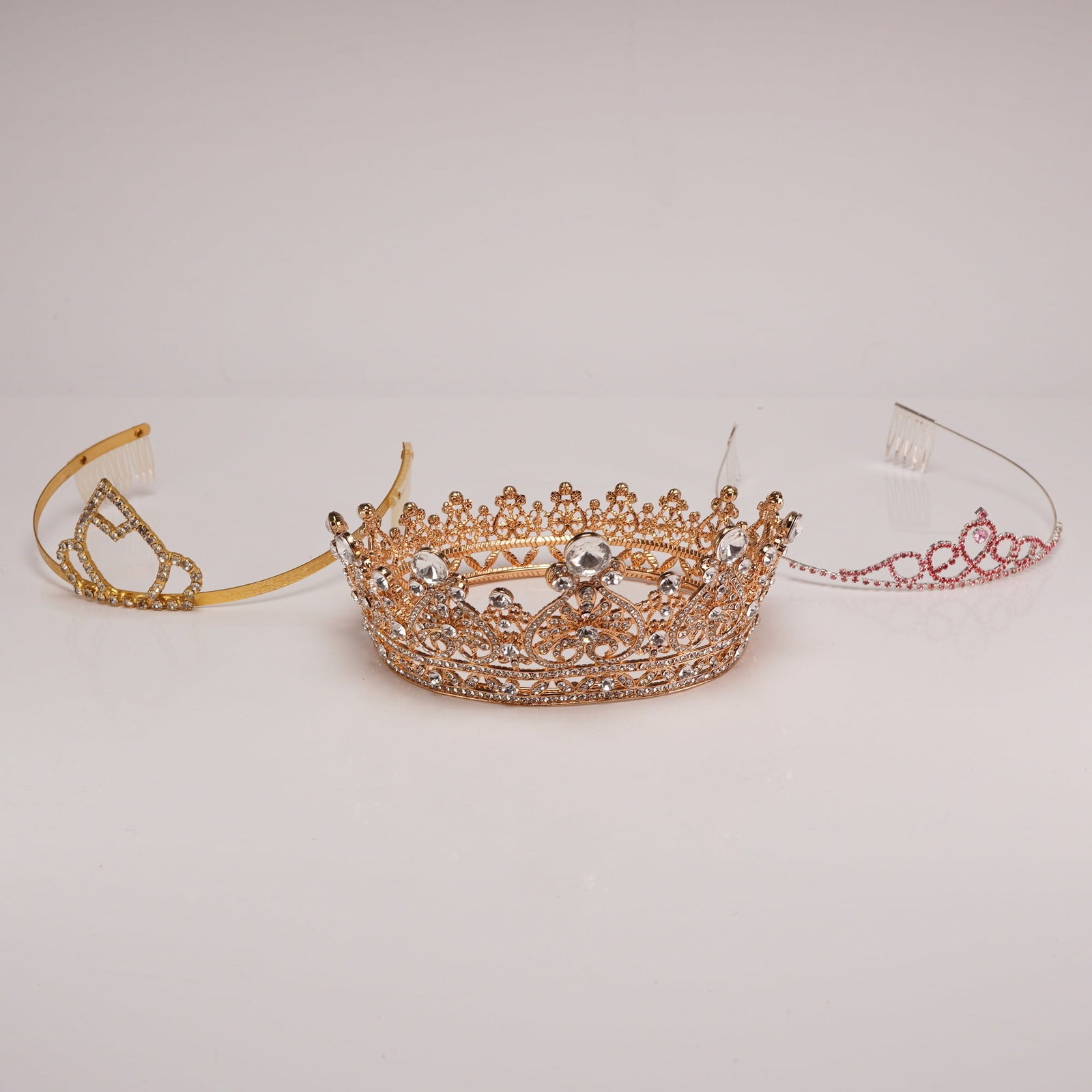 3pc Jewel Studded Tiaras and Crowns w/ Rhinestones: A set of three jewel studded costume jewelry headpieces, including one full-circle crown and two front-facing tiaras. The collection consists of unmarked base metal pieces with gold-tone and silver-to