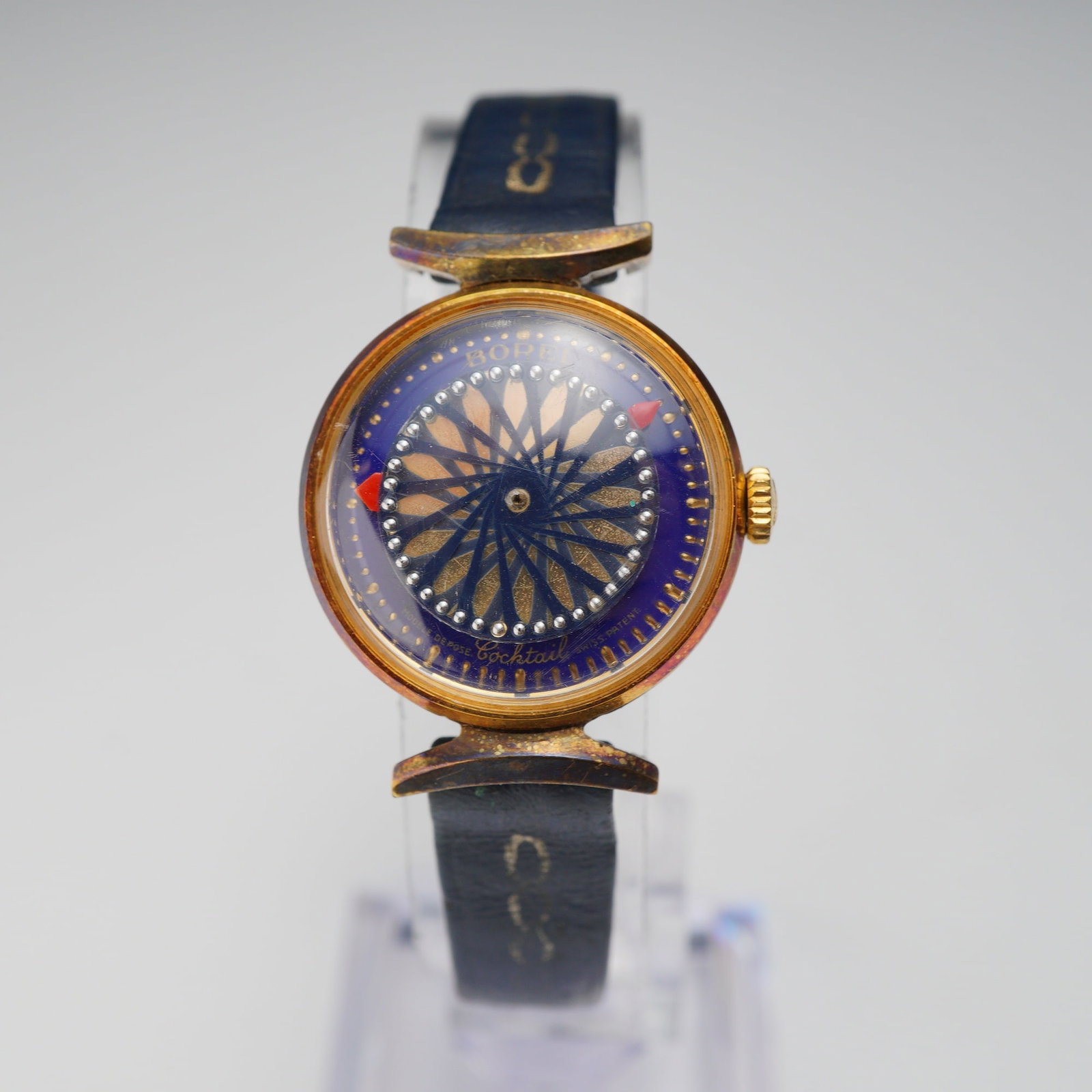 Ernest Borel Cocktail Kaleidoscope Ladies Wristwatch: A ladies Ernest Borel Cocktail wristwatch featuring a kaleidoscopic dial. The timepiece is constructed with a gold-tone metal case, likely gold-plated, and features an exhibition case back. The dial i