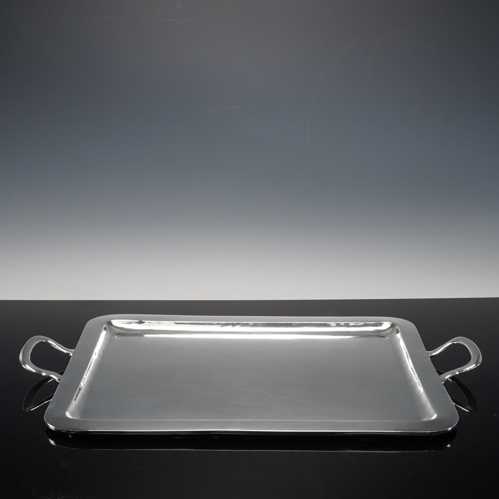 925 Sterling Silver Handled Tray 1900 grams: Large rectangular Mexican 925 sterling silver tray featuring smooth, hand-hammered surfaces and integrated curved handles at each end. A fine example of mid-century Mexican silversmith, this tray show