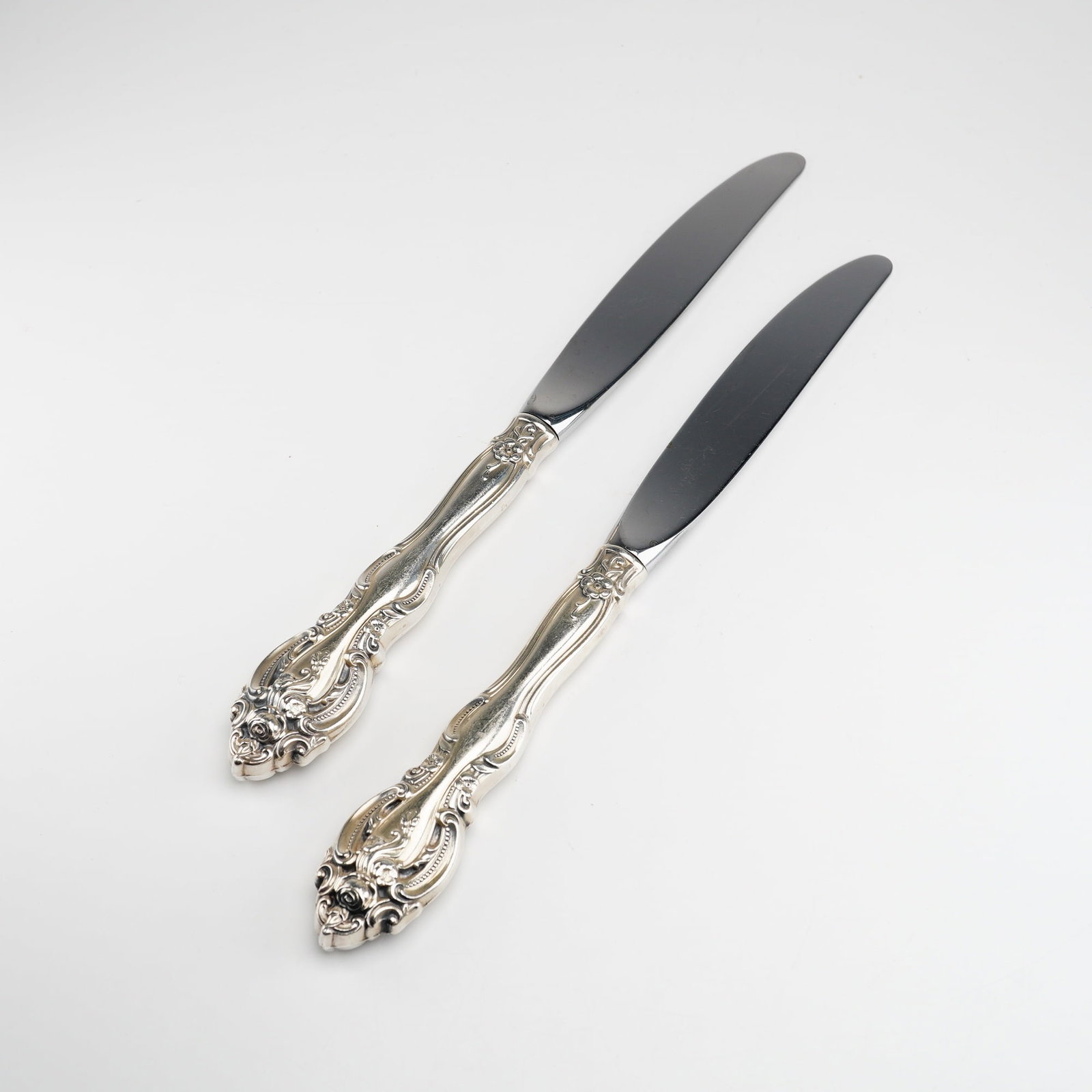 2pc Gorham Sterling Silver and Stainless Steel Dinner Knives, La Scala: This pair of dinner knives was produced by the Gorham Manufacturing Company in the highly decorative La Scala pattern. Characterized by its Rococo-revival aesthetic, the pattern features dense scrollw
