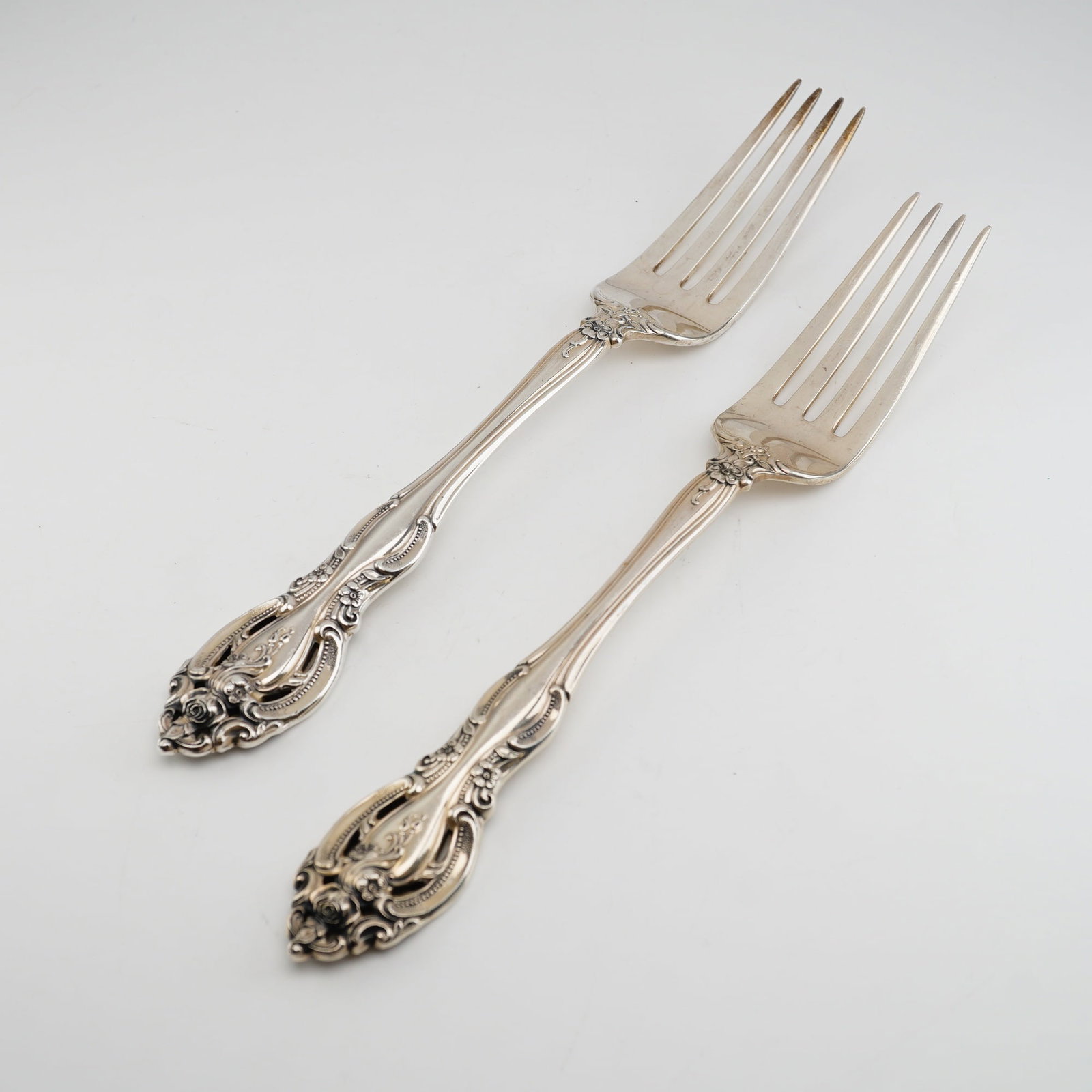 2pc Gorham Sterling Silver Dinner Forks, La Scala: Rococo-revival design featuring elaborate scrollwork, floral motifs including roses, and distinctive pierced openwork handles. Each fork features four tines and deep repousse decoration that continues