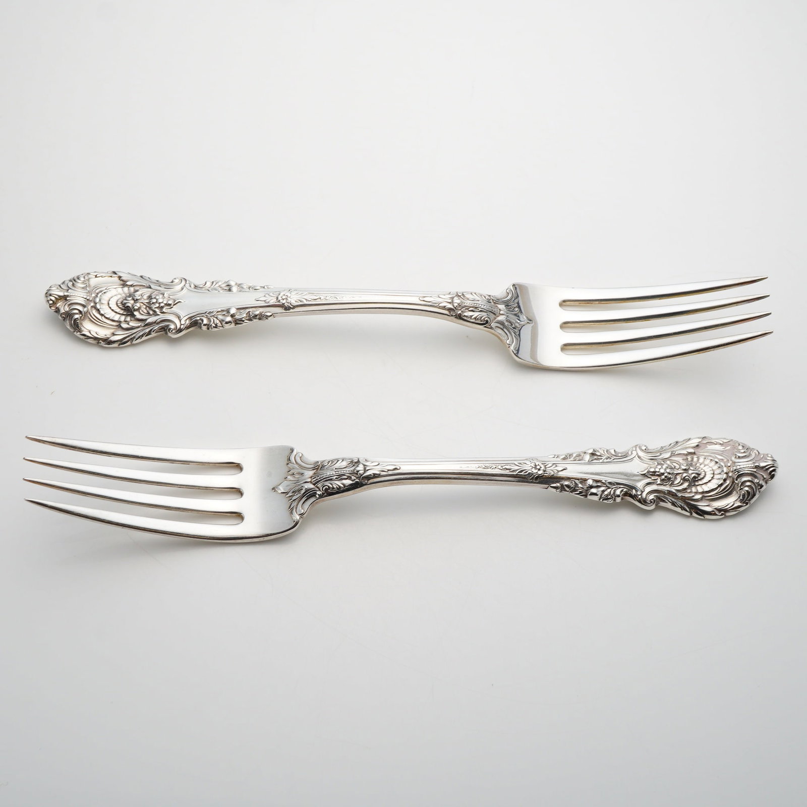 A Pair of Wallace Sterling Silver Dinner Forks in the Sir Christopher Pattern: This pair of solid sterling silver dinner forks is manufactured by Wallace Silversmiths in the Sir Christopher pattern. First introduced in 1936, this Rococo-revival pattern features ornate handles de