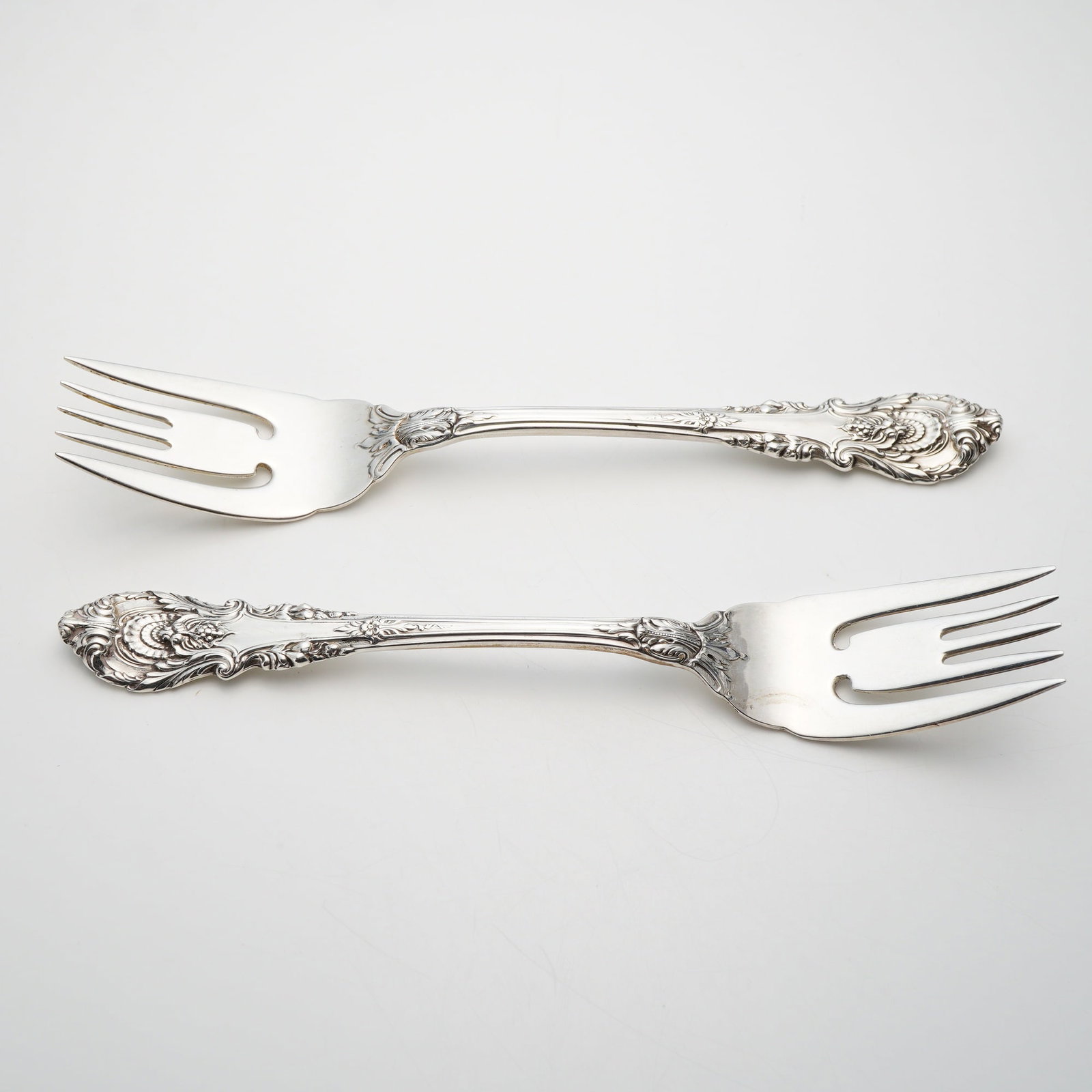 A Pair of Wallace Sterling Silver Salad Forks in the Sir Christopher Pattern: This is a pair of solid sterling silver salad forks manufactured by Wallace Silversmiths in the Sir Christopher pattern. The handles are elaborately decorated in the Rococo Revival style, featuring de