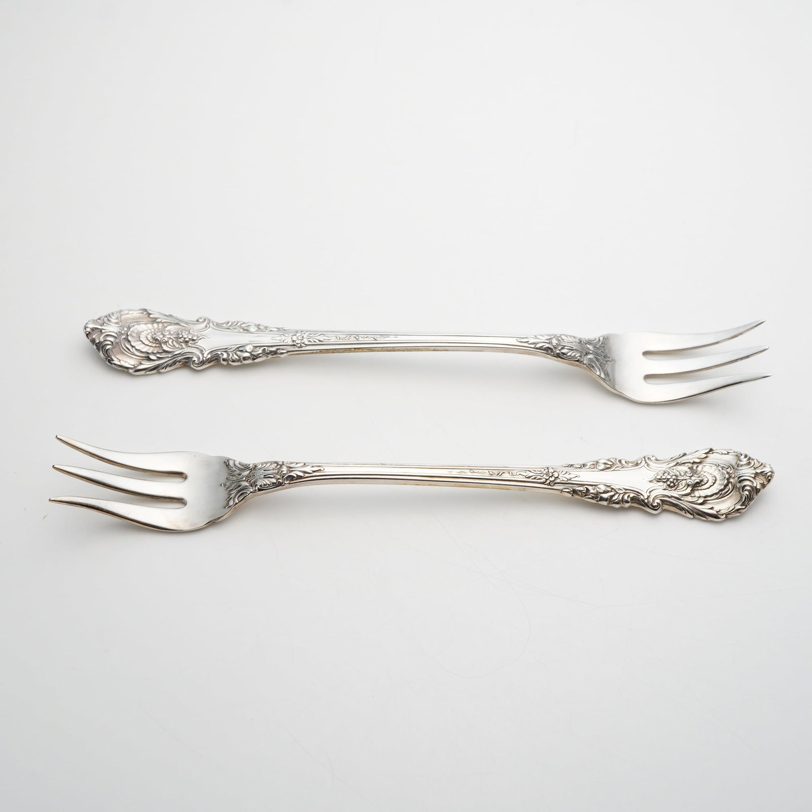 A Pair of Wallace Sterling Silver Sir Christopher Pattern Cocktail Forks: A pair of sterling silver cocktail or seafood forks manufactured by Wallace Silversmiths in the Sir Christopher pattern. This pattern, designed by William S. Warren and introduced in 1936, is a promin