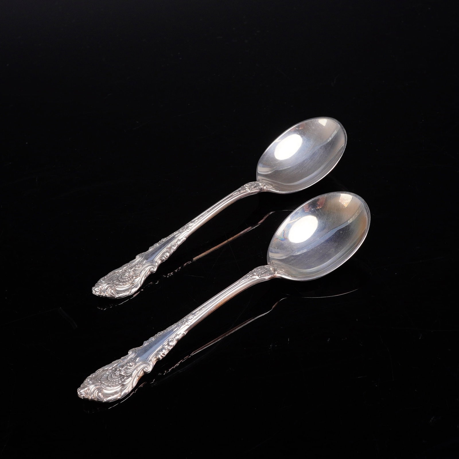 A Pair of Wallace Sterling Silver Soup Spoons in the Sir Christopher Pattern: A pair of sterling silver soup spoons manufactured by Wallace Silversmiths in the Sir Christopher pattern. This highly ornate pattern features handles decorated with deep scrolls, shell motifs, and ac
