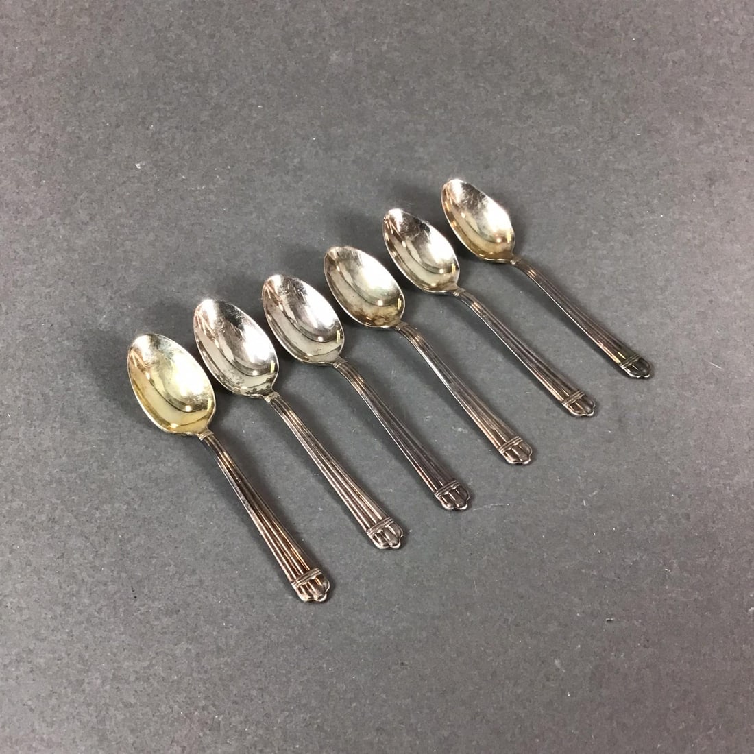 Set of 6 Christofle Silver Plated Teaspoons, Aria Pattern: A set of 6 silver plated tea spoons manufactured by Christofle in France. The spoons are designed in the Aria pattern, which features a classic reeded handle accented by decorative banding at both the