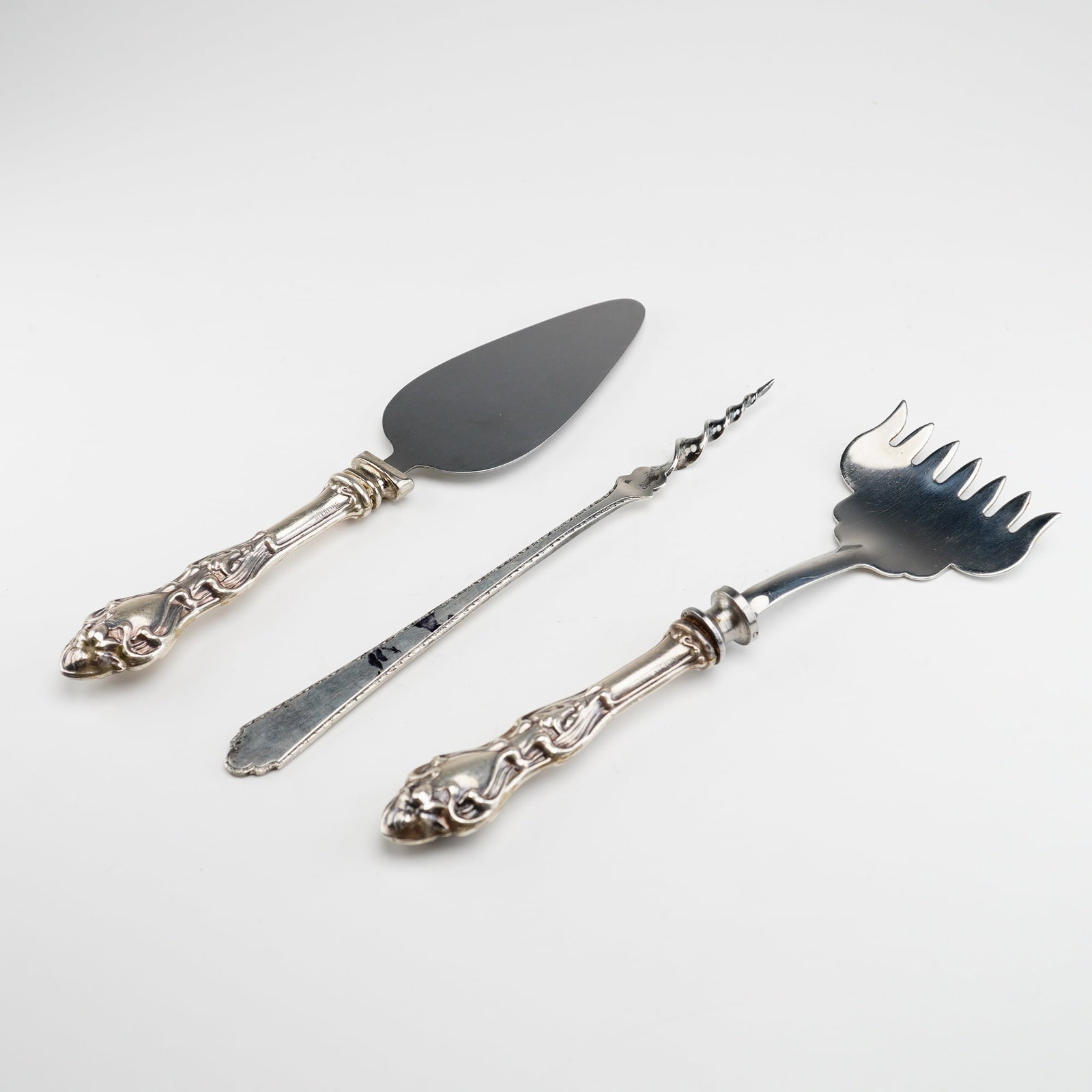 3pc Lunt Treasure Sterling Silver and Stainless Serving Pieces: The group includes a small server, a multi-tined serving fork, and a decorative pick. The server and fork feature weighted sterling silver handles with ornate relief decoration consisting of stylized 