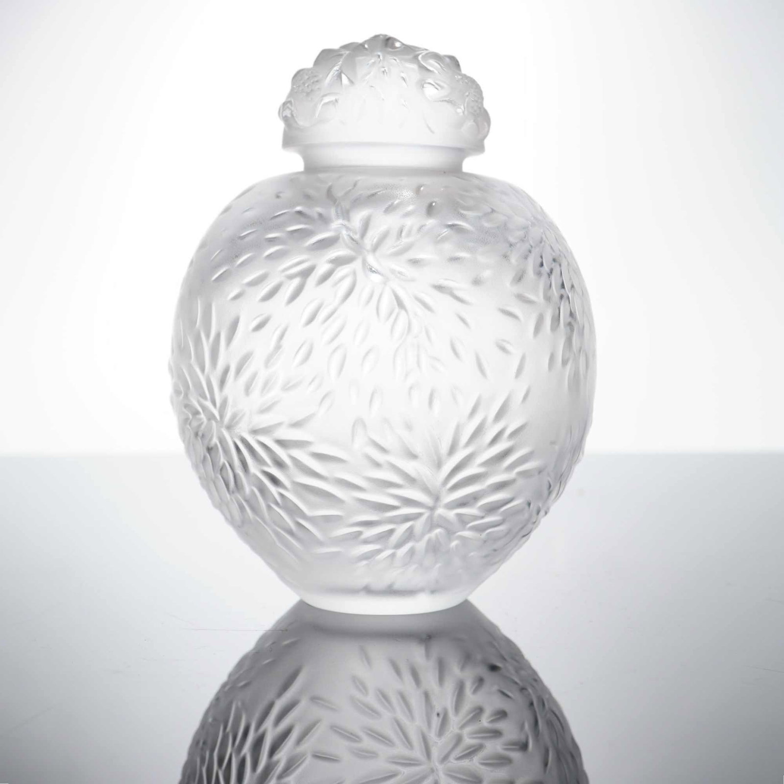 Lalique Frosted Crystal Lidded Caddy, Kati: This globular vessel is constructed from mold-pressed crystal with a signature satin-frosted finish. The exterior body features a high-relief design of radiating petals, while the matching lid is deco