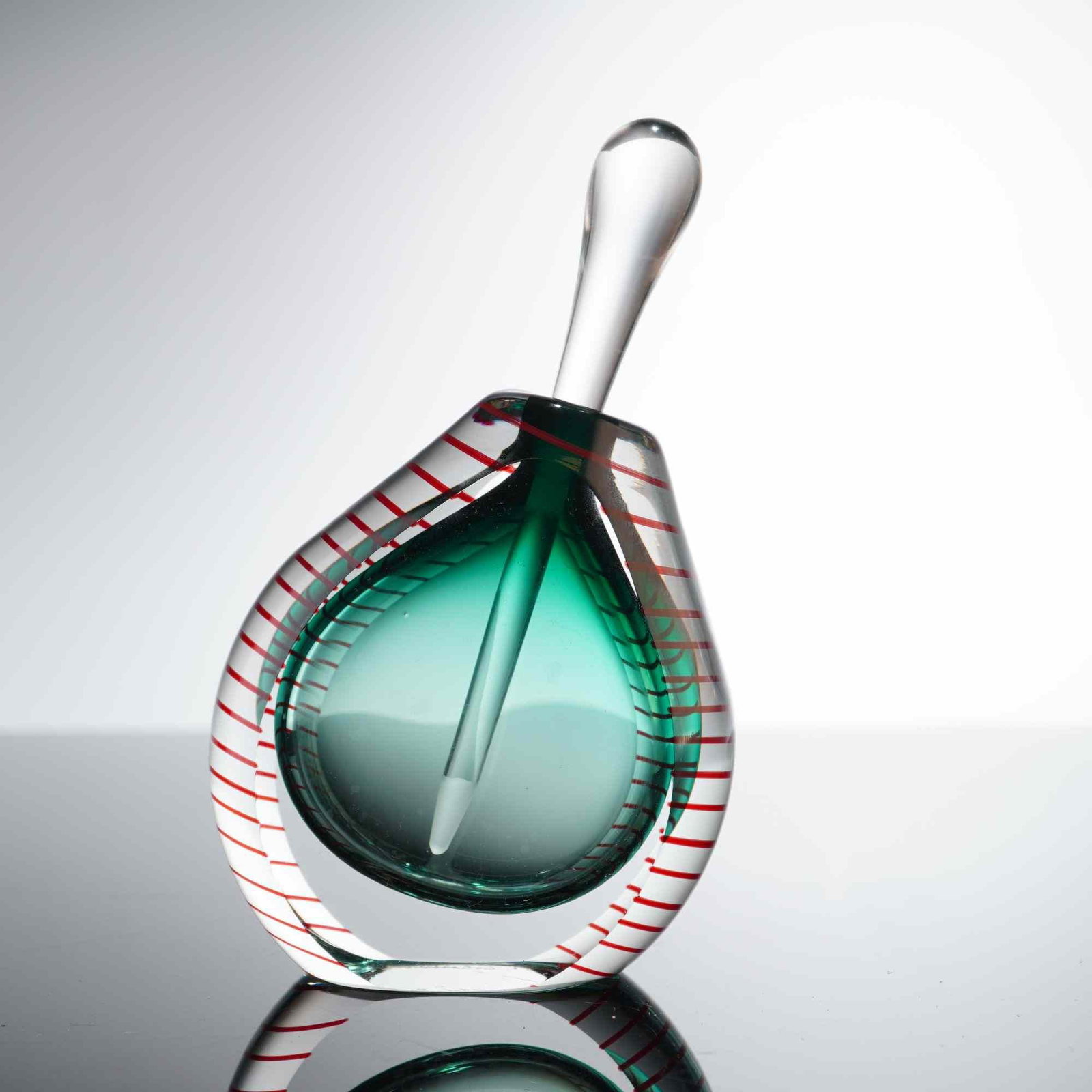 Fire Island Studio by David Foster and Matthew LaBarbera Art Glass Perfume Bottle: The vessel is constructed in a weighted teardrop form featuring a translucent teal-green interior core encased in a thick layer of clear glass. The exterior is decorated with a fine, spiraling red fil