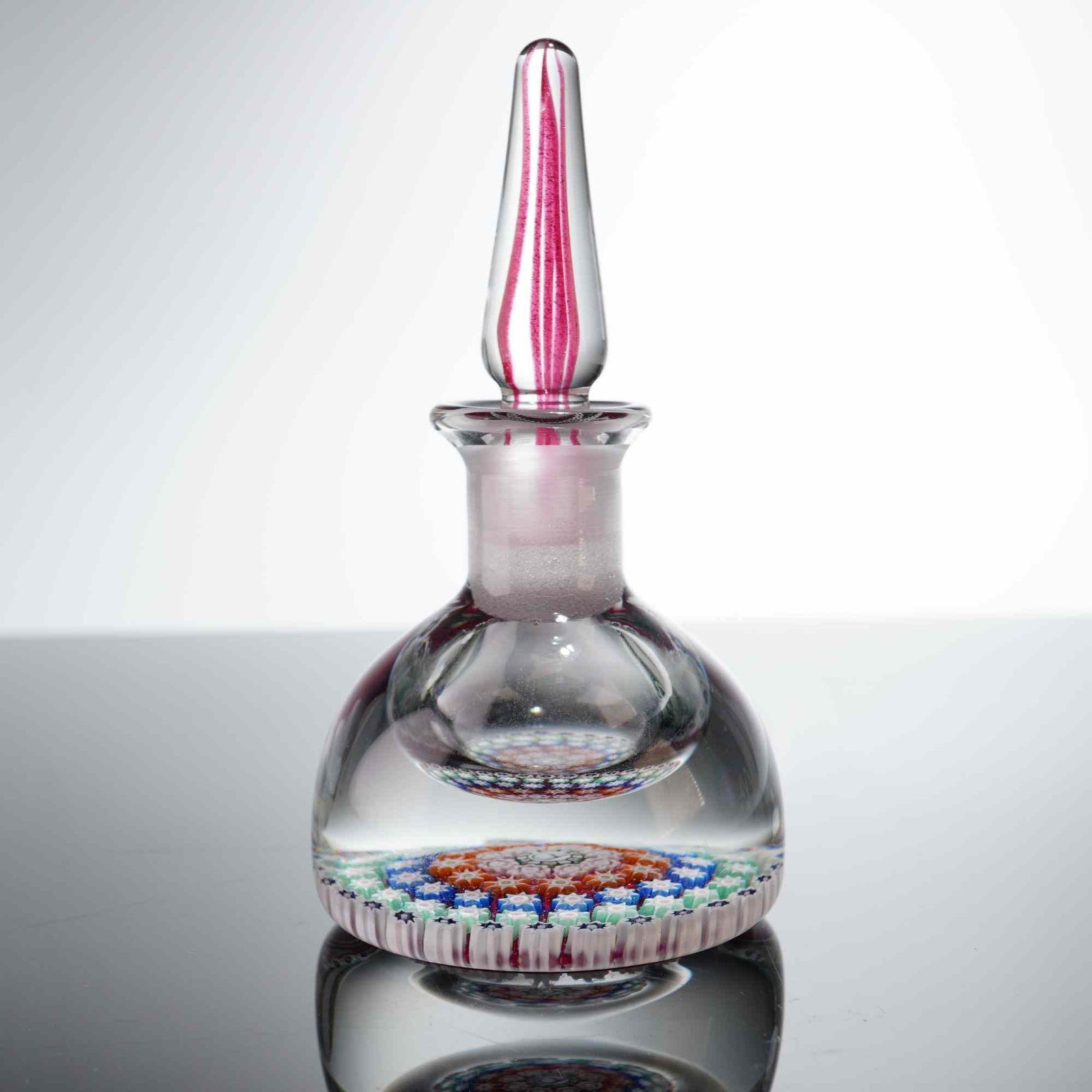 Perthshire Style Millefiori Art Glass Perfume Bottle and Stopper, 1995: This Perthshire art glass perfume bottle and stopper features intricate millefiori decoration within a heavy, clear glass bulbous body. The design showcases a concentric millefiori carpet at the base,