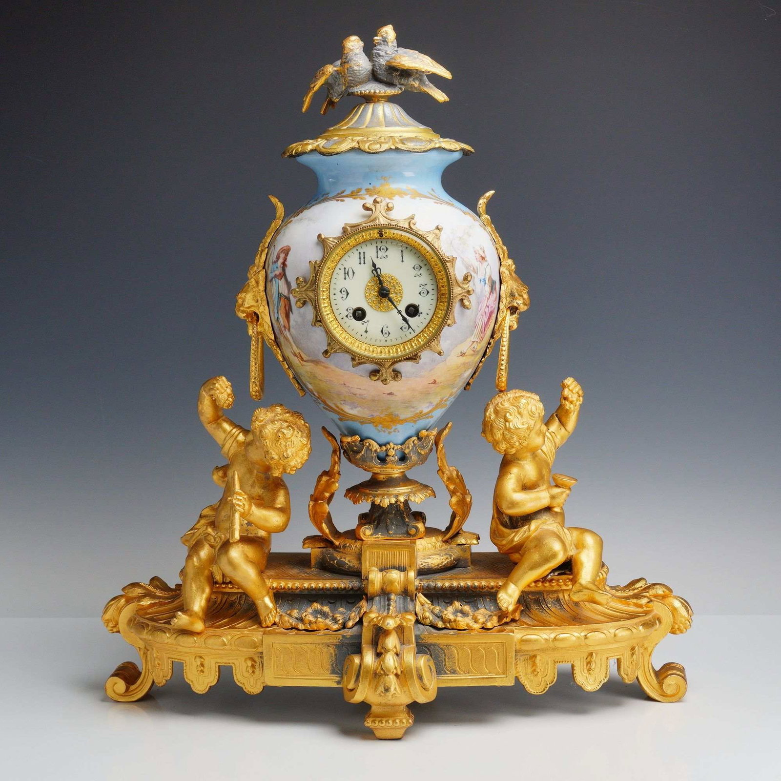 French Rococo Style Porcelain and Ormolu Mantel Clock by Samuel Marti: This 19th-century French mantel clock is manufactured by Samuel Marti et Cie, featuring a Rococo revival design. The central body is an urn-form celeste blue porcelain vessel decorated with hand-paint