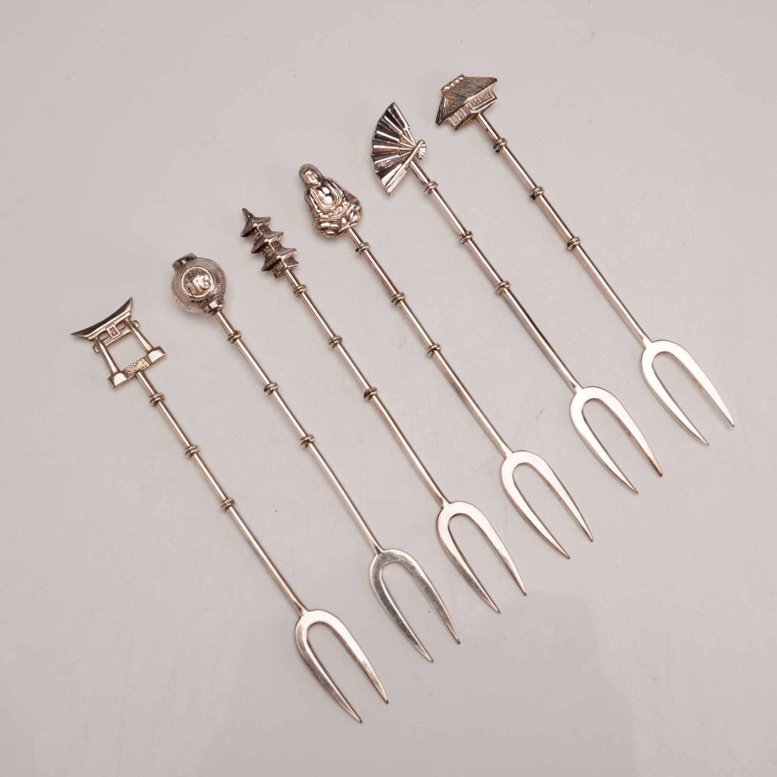 6pc Japanese Sterling Silver Bamboo Motif Olive Picks: A set of six vintage sterling silver olive picks manufactured in Japan. Each piece is constructed with a slender handle designed to resemble a segmented bamboo stalk. The set features six distinct cas