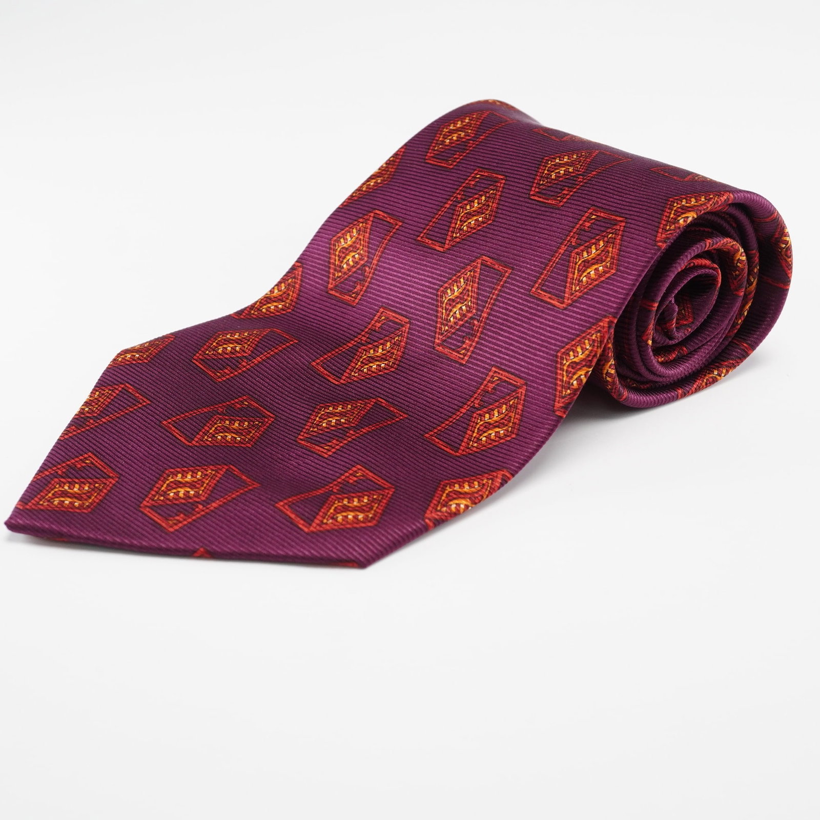 Valentino Plum Silk Geometric Necktie, Made in Italy: A Valentino necktie, crafted from 100% silk (100% SETA) and made in Italy. The tie features a ribbed dark plum or deep reddish-purple ground, adorned with a repeating geometric pattern of stylized, op