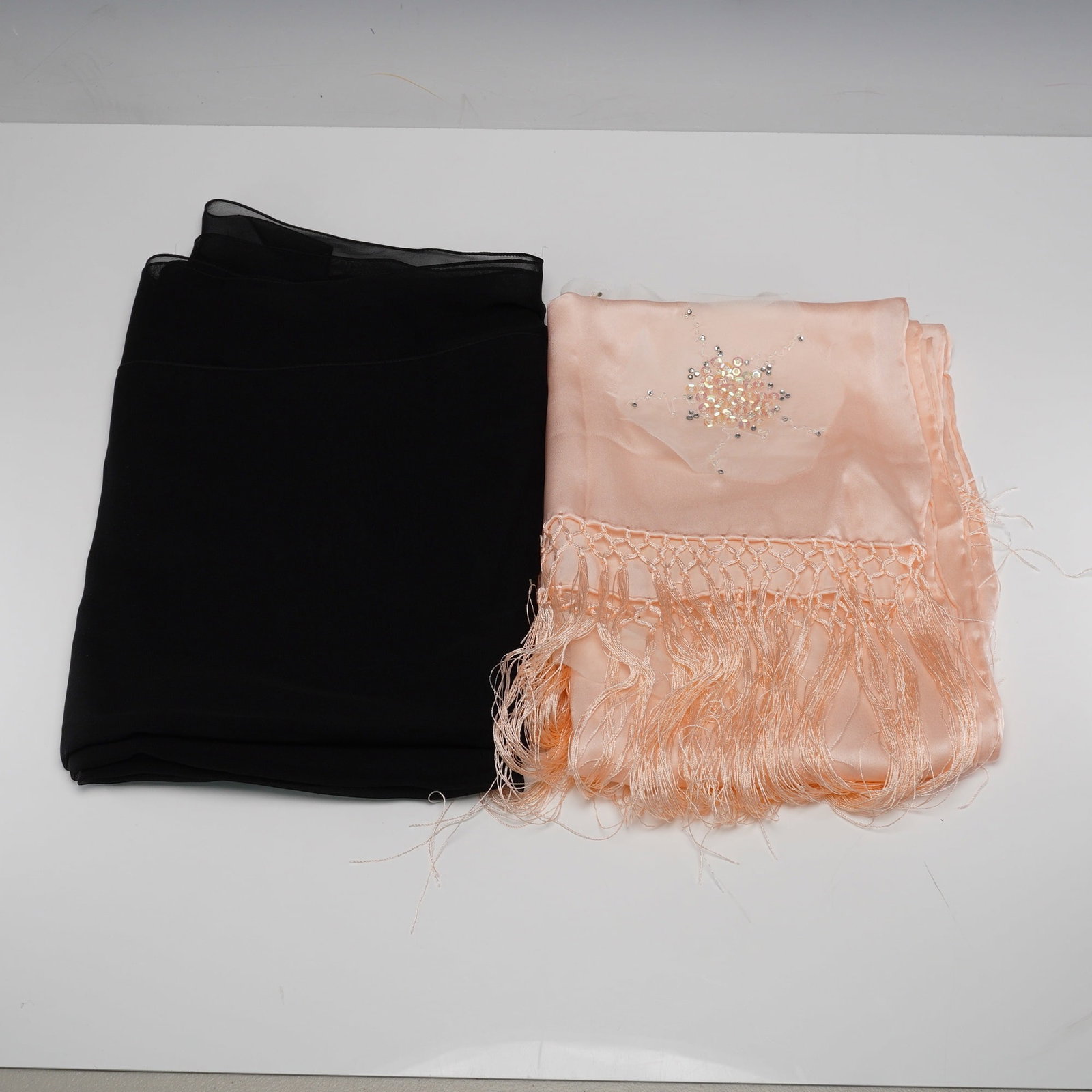 Two Contemporary Scarves, including an Emporio Armani: An Emporio Armani peach colored silk scarf with a knotted fringe border, embellished with iridescent sequins and small silver colored beads in decorative patterns, accompanied by a sheer black scarf. 