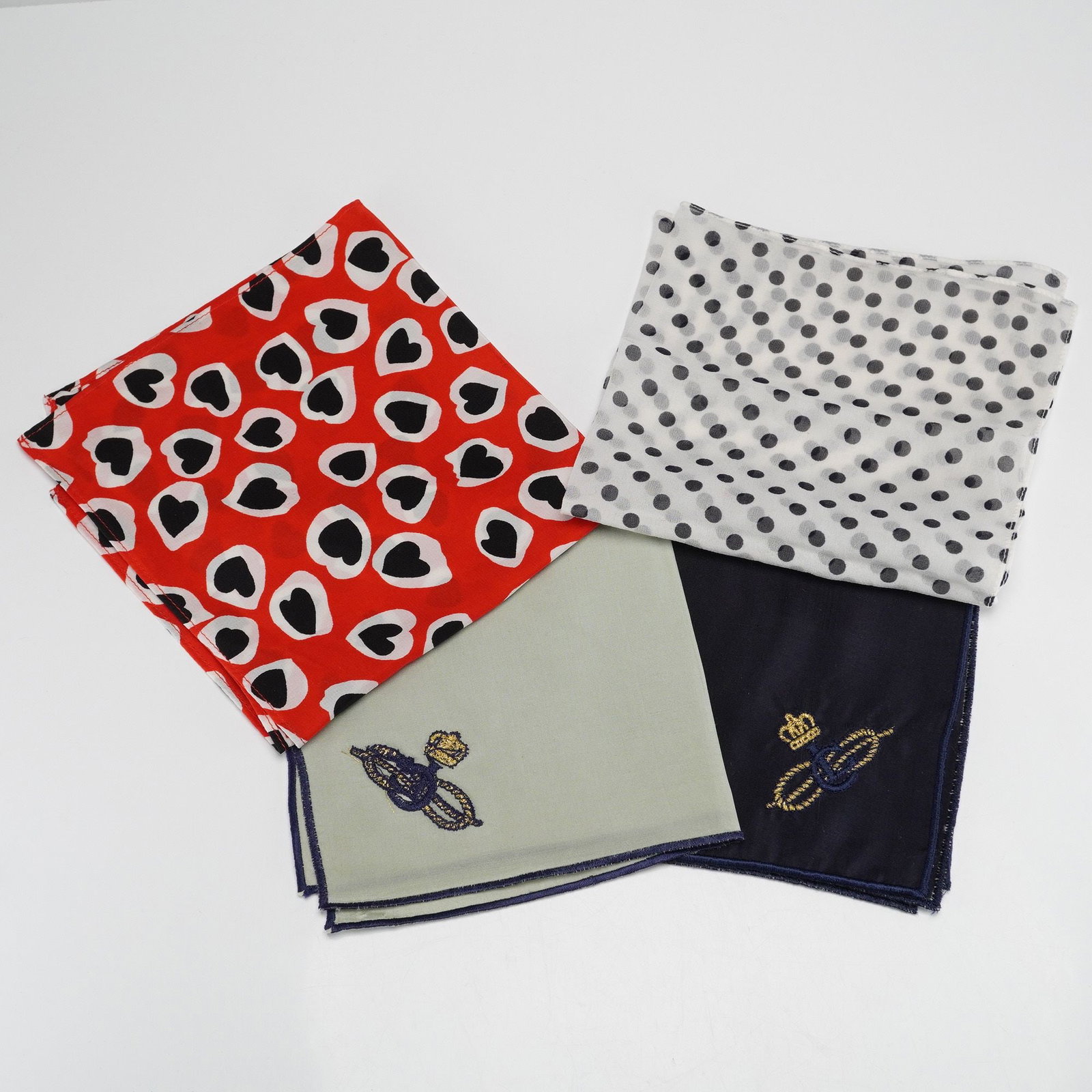 A Group of Four Assorted Silk and Textile Pocket Squares: A group of four pocket squares that include one in red with irregular black hearts, some outlined in white, and another in sheer white with scattered black polka dots. The two solid pocket squares are